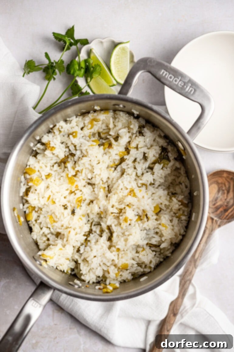 A large saucepan filled with freshly cooked, fluffy cilantro lime rice, with a wooden spoon resting nearby, inviting you to serve yourself.