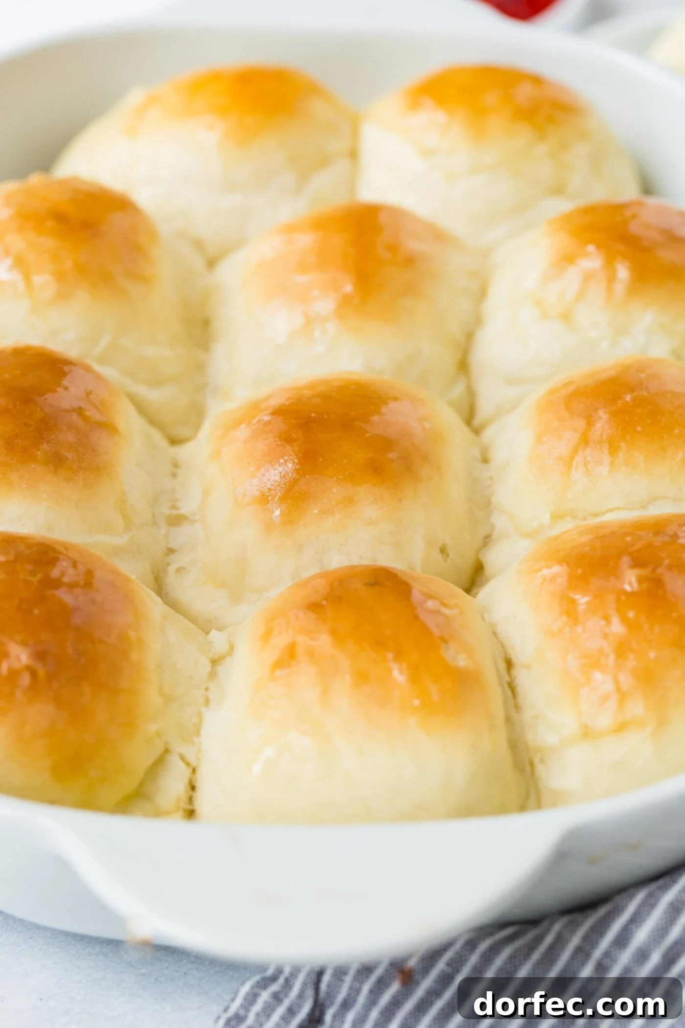 A pan of white dinner rolls that have been baked to a soft golden brown.