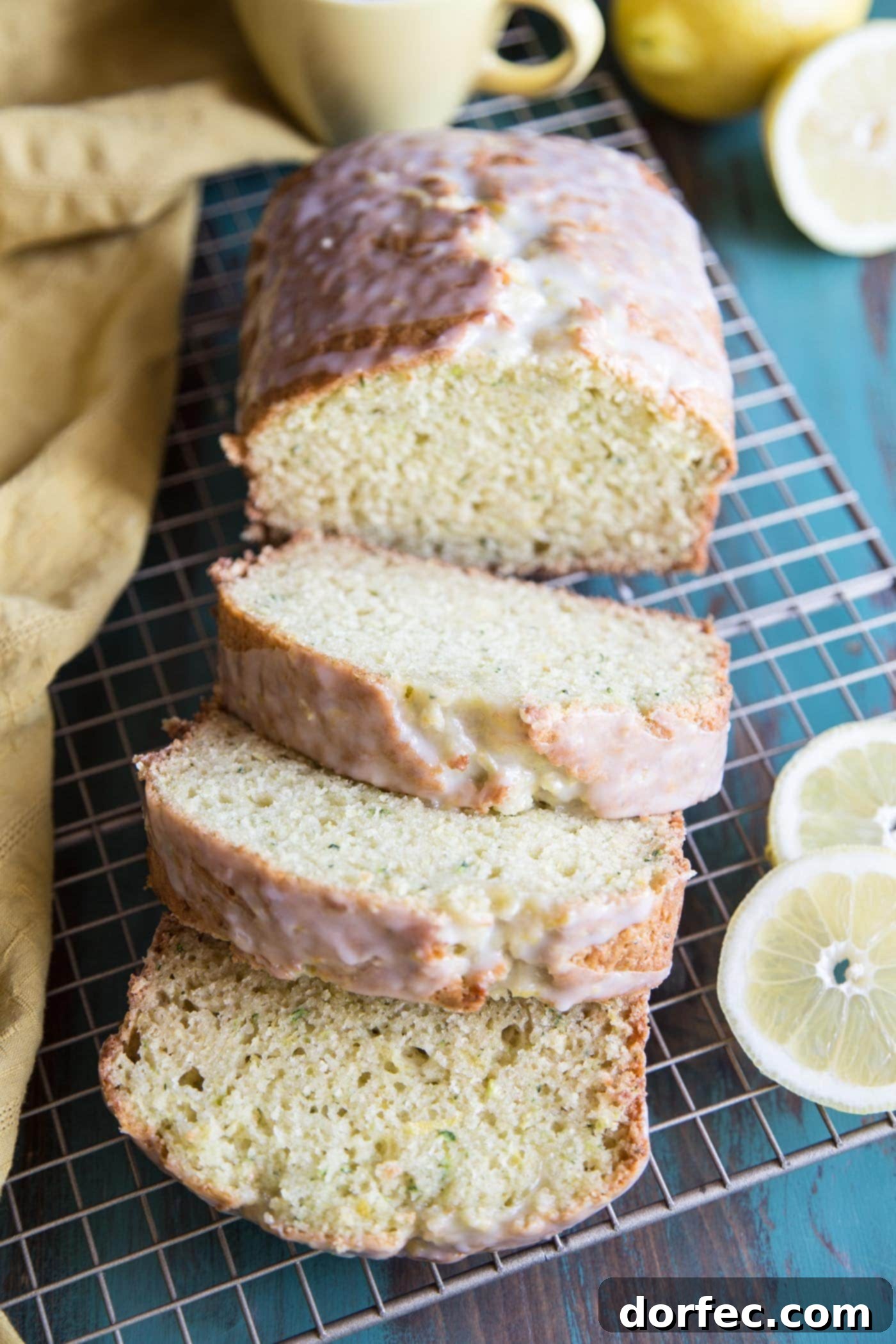 Sliced lemon zucchini bread on a wire rack, garnished with fresh lemon slices and mint leaves