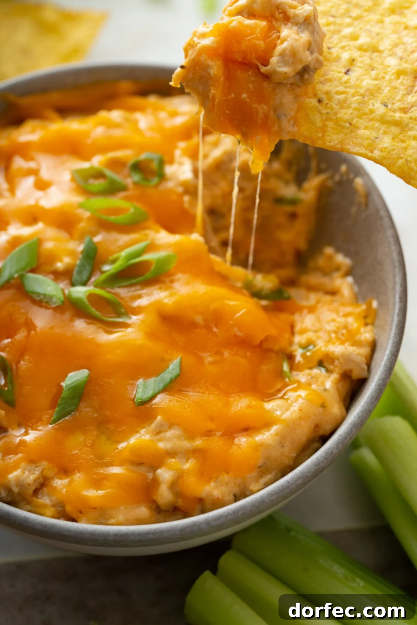 Warm Slow Cooker Buffalo Chicken Dip A close-up of warm slow cooker buffalo chicken dip, topped with perfectly melted cheese and a sprinkle of fresh chopped green onions, showcasing its inviting texture.