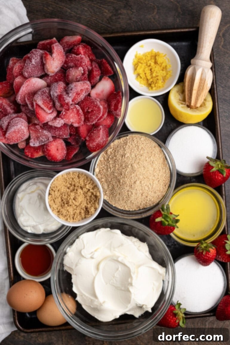 Strawberry Cheesecake Bites 3 Various ingredients for a creamy berry cheesecake dessert, including fresh strawberries, lemons, blocks of cream cheese, butter, and graham crackers, neatly arranged on a baking sheet.