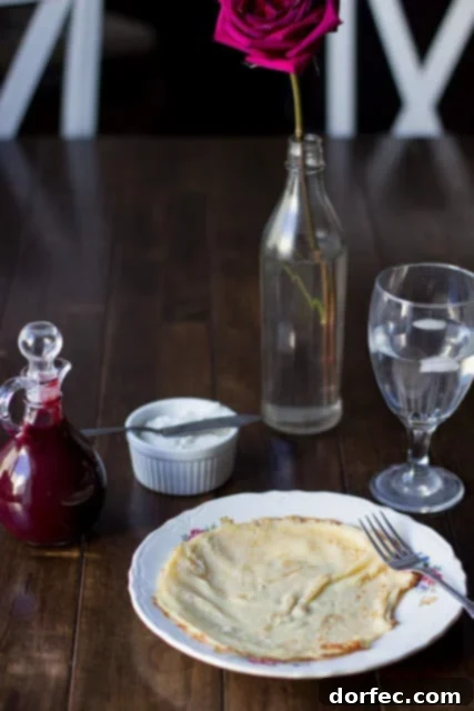 Marionberry Strawberry Syrup served over the most delicious cream filled crepes. #Breakfast at our house is amazing. ohsweetbasil.com Close-up of Marionberry Strawberry Syrup generously coating cream-filled crepes, emphasizing a truly amazing breakfast experience. Visit ohsweetbasil.com for the recipe.