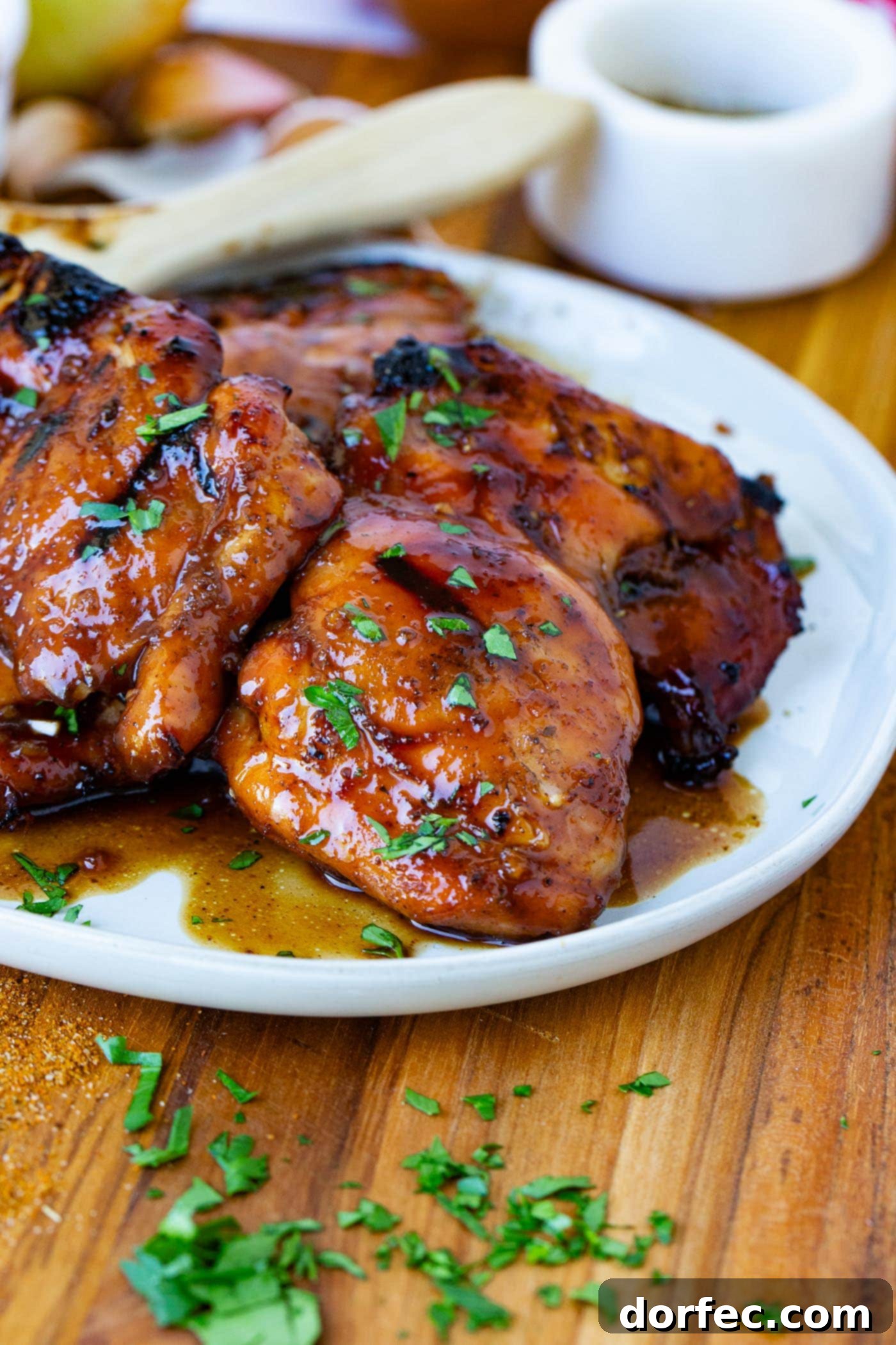 A serving plate of marinated smoked chicken thighs sprinkled with fresh green herbs.