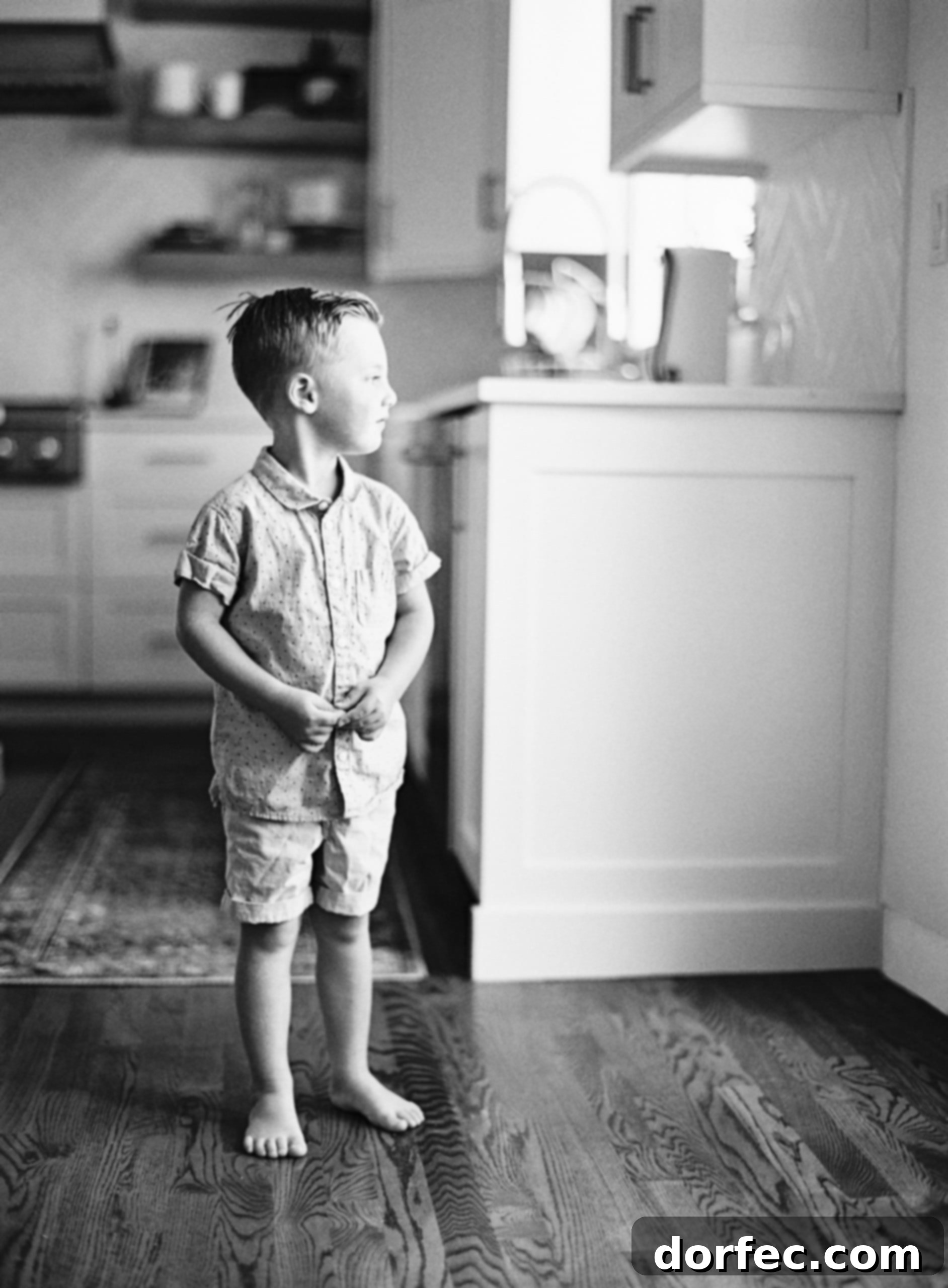 A young boy with thoughtful expression gazes out a window, reflecting on the world outside.