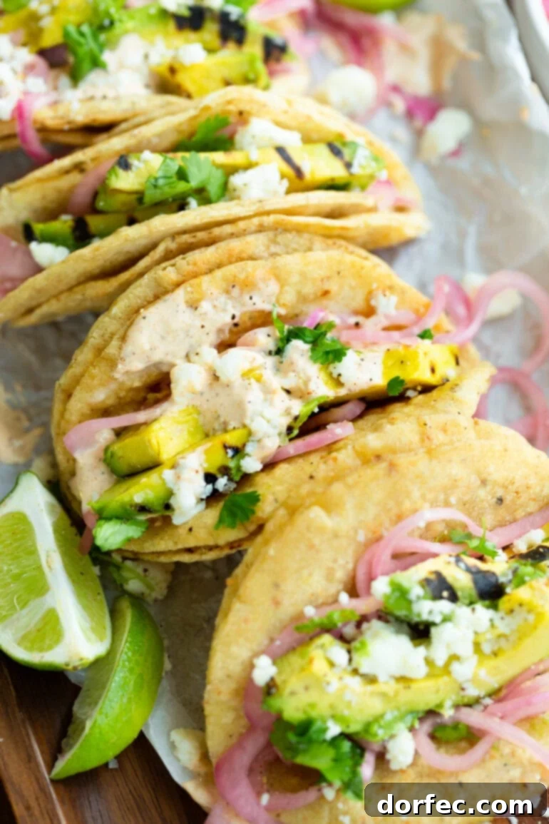Smoky Grilled Avocado Tacos 2 A photo of grilled avocado tacos topped with pickled red onions, crumbled queso fresco, and a tangy lime crema.
