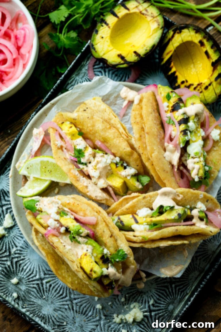 Smoky Grilled Avocado Tacos 3 A photo of several grilled avocado tacos all sitting on a plate.
