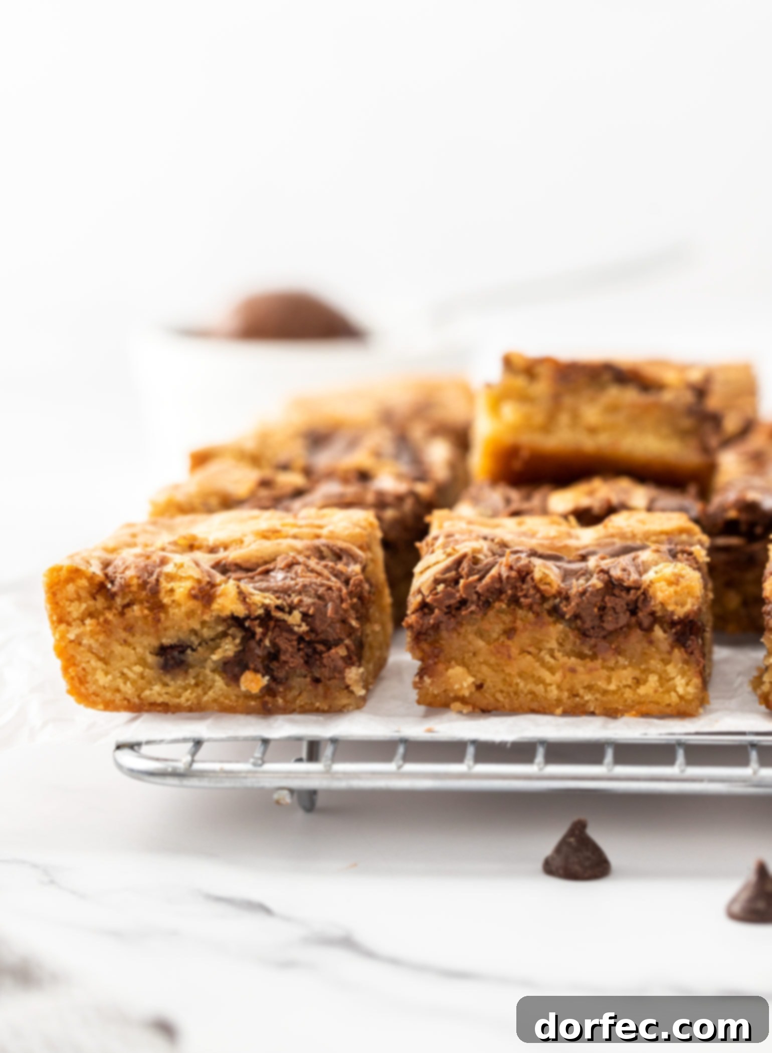 A batch of nutella blondies sitting on a wire rack, perfectly cooled and ready to be cut and served.