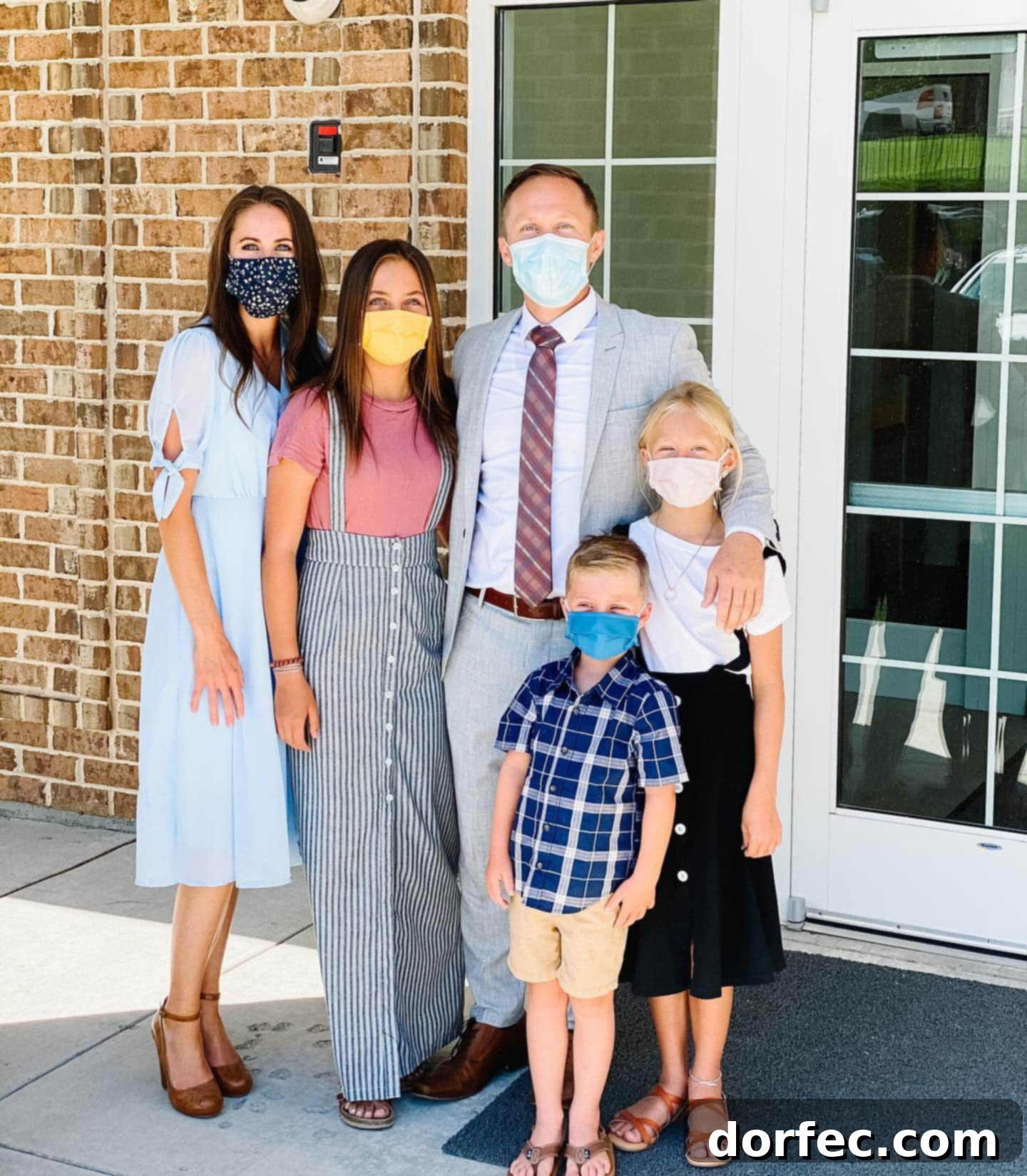 A photo of a family all wearing masks outside of a church building.