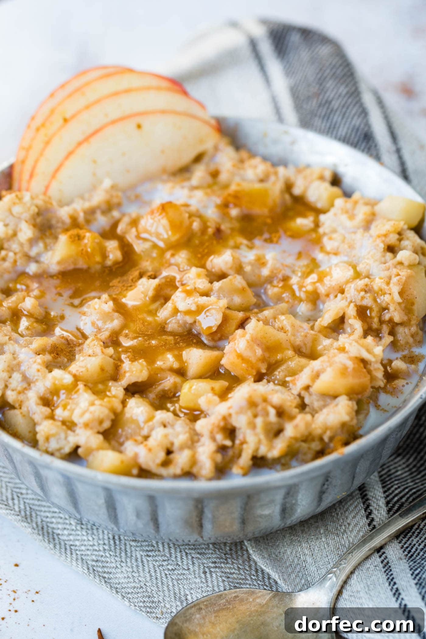A photo of apple pie slow cooker oatmeal topped with caramel and thinly sliced apples.