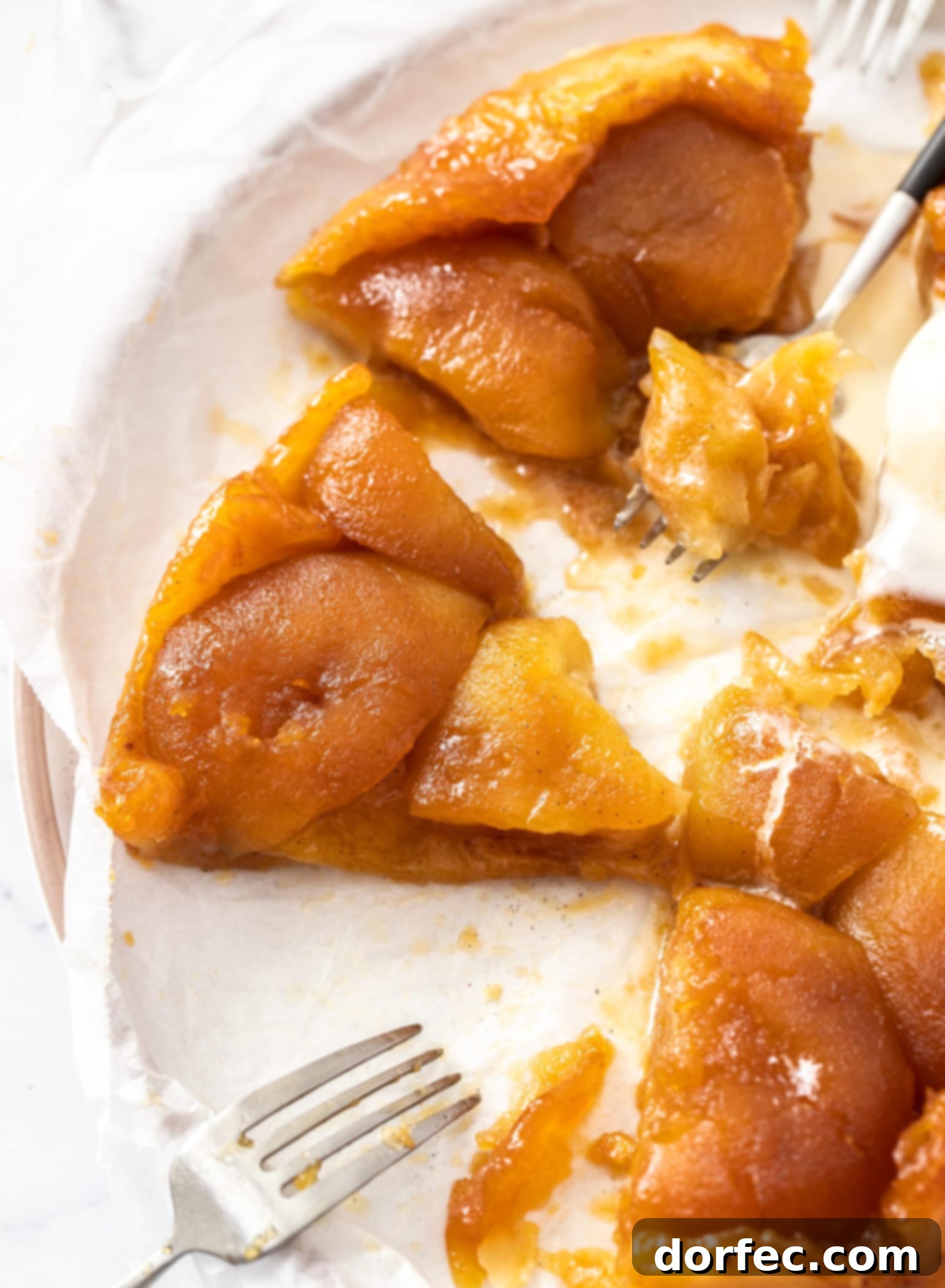 Caramelized Apple Tarte Tatin 3 A close-up shot of a slice of Apple Tarte Tatin, showing the layers of caramelized apple and flaky puff pastry, served with two forks, inviting a delicious taste.
