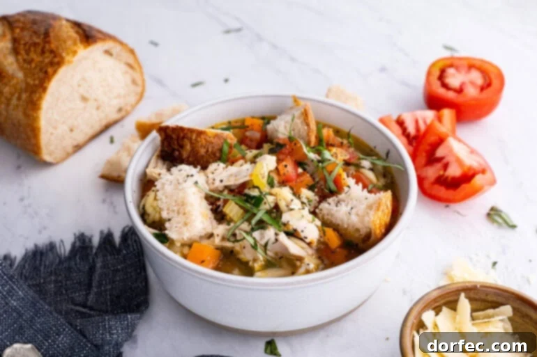 A white soup bowl filled with Instant Pot Italian Chicken Soup, topped generously with chunks of crusty bread, ready to be enjoyed.