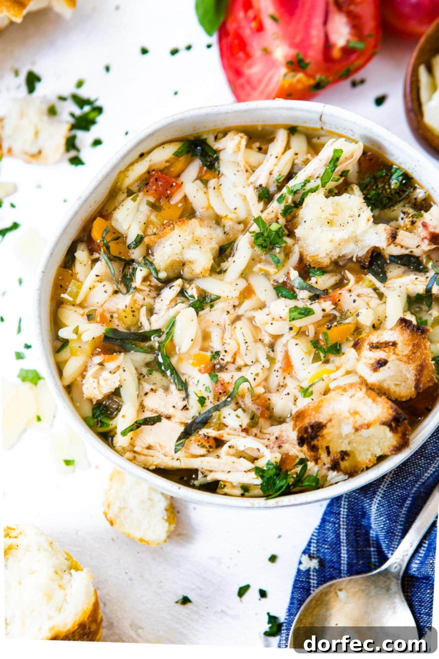 A large white soup bowl filled with Instant Pot Italian Chicken Soup, garnished with chopped fresh parsley and crusty bread slices, ready to serve.