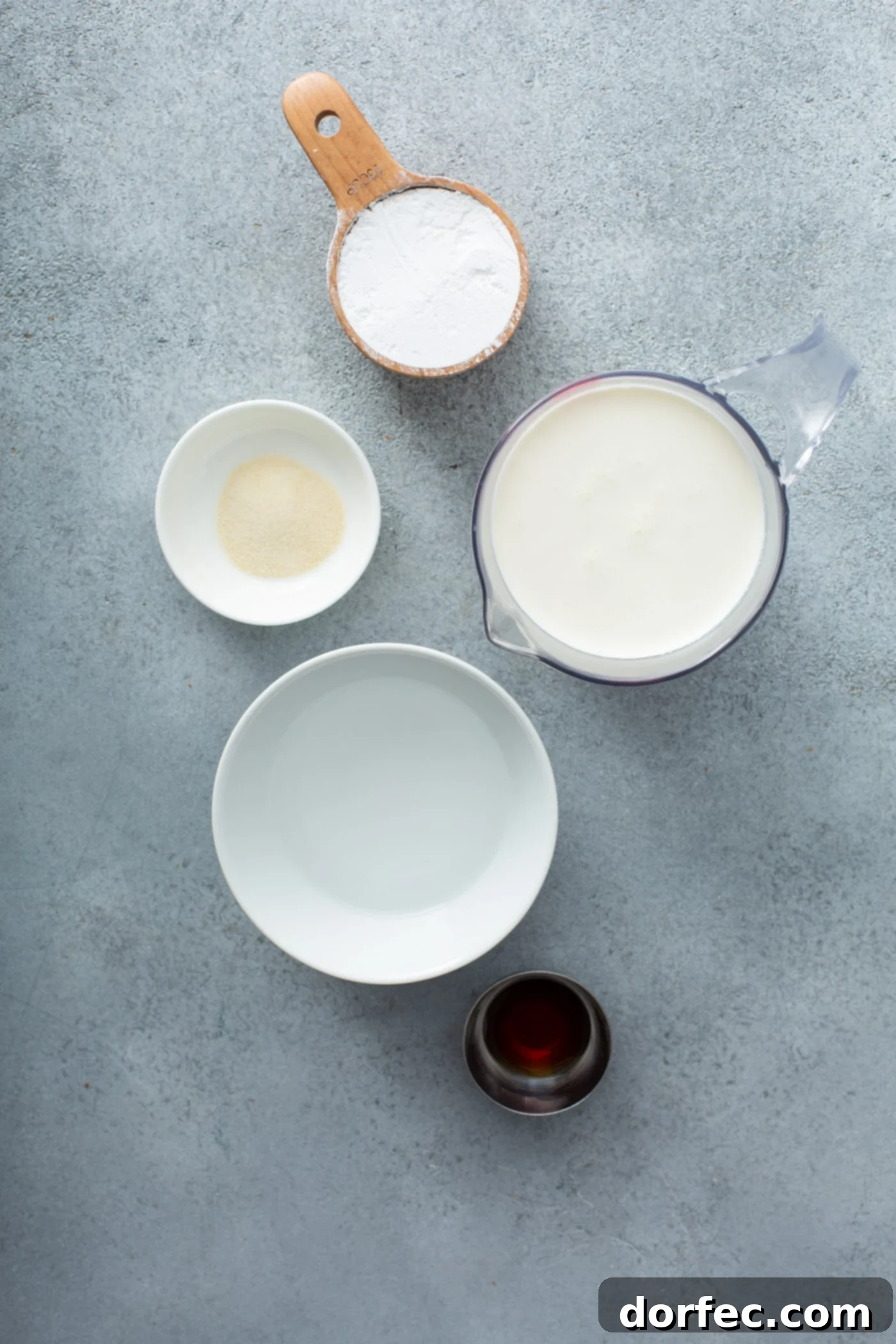 Stabilized Whipped Cream Ingredients Various ingredients laid out for making stabilized whipped cream: containers of cold heavy whipping cream, powdered sugar, vanilla extract, a small bowl of water, and a packet of unflavored gelatin.