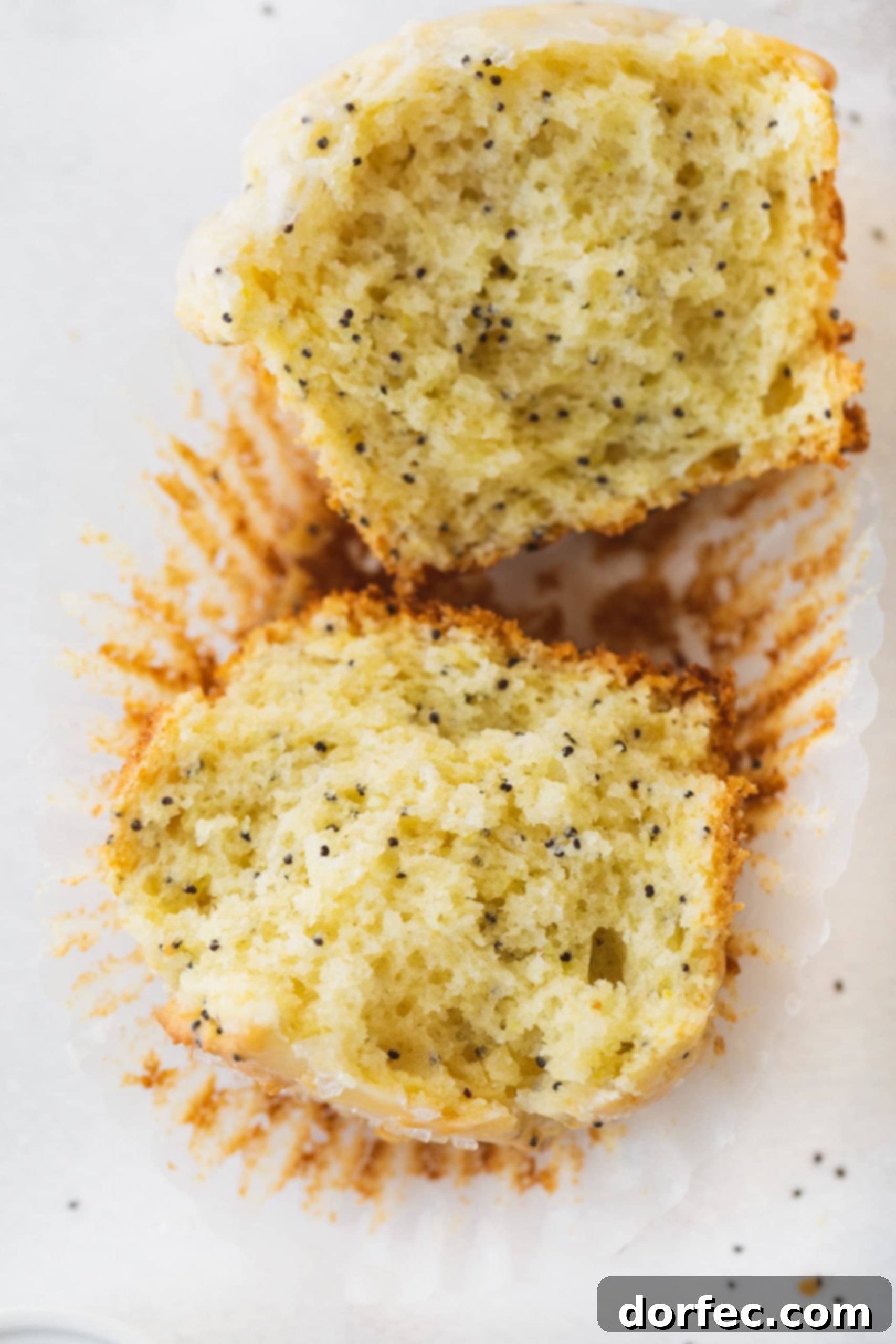 Lemon Poppy Seed Muffins A perfectly baked lemon poppy seed muffin, sliced in half, reveals its moist, tender crumb speckled with poppy seeds. This close-up highlights the texture and inviting internal structure of the muffin.