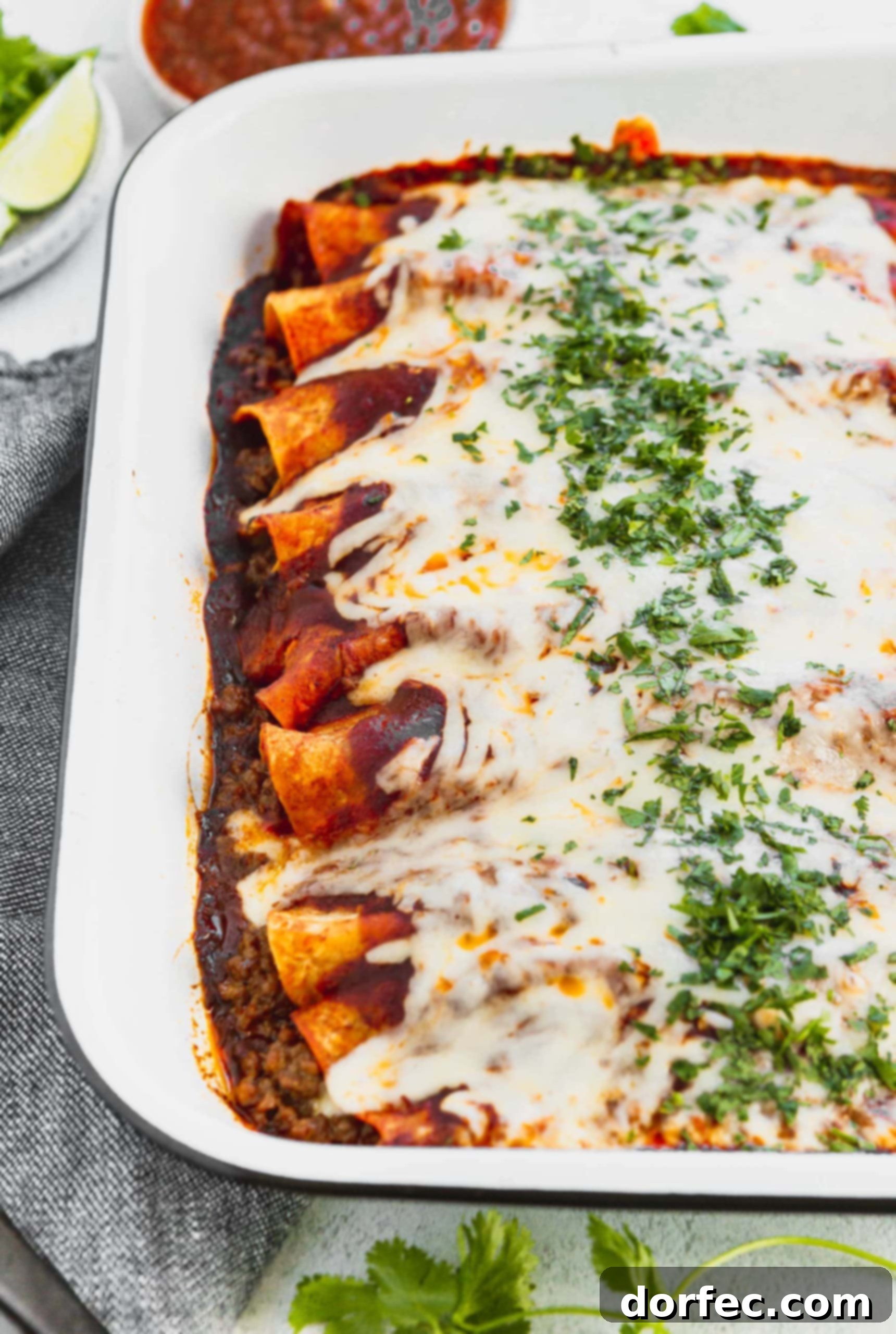 A photo of a pan of beef enchiladas covered in melted cheese and finely chopped cilantro.