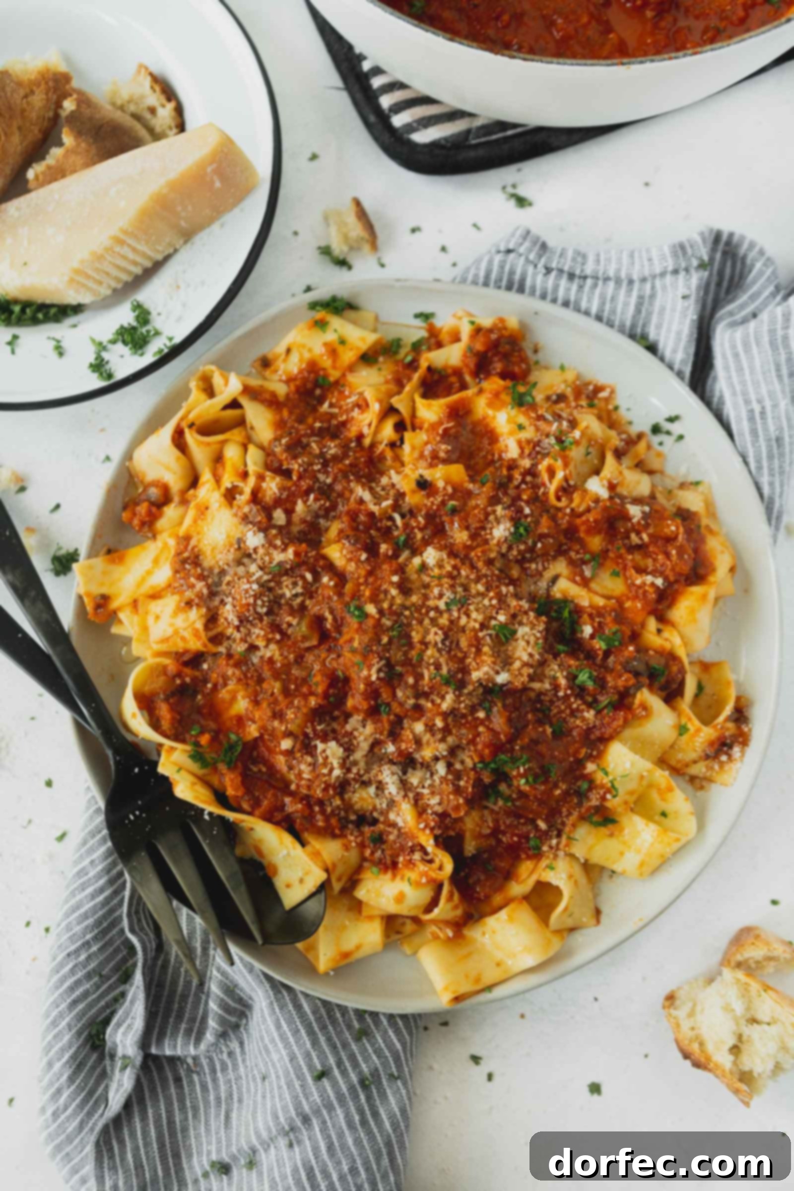 A dinner plate of pasta topped with vegan bolognese sauce. It is a thick red sauce, garnished with fresh cilantro leaves, with a fork resting beside the pasta.