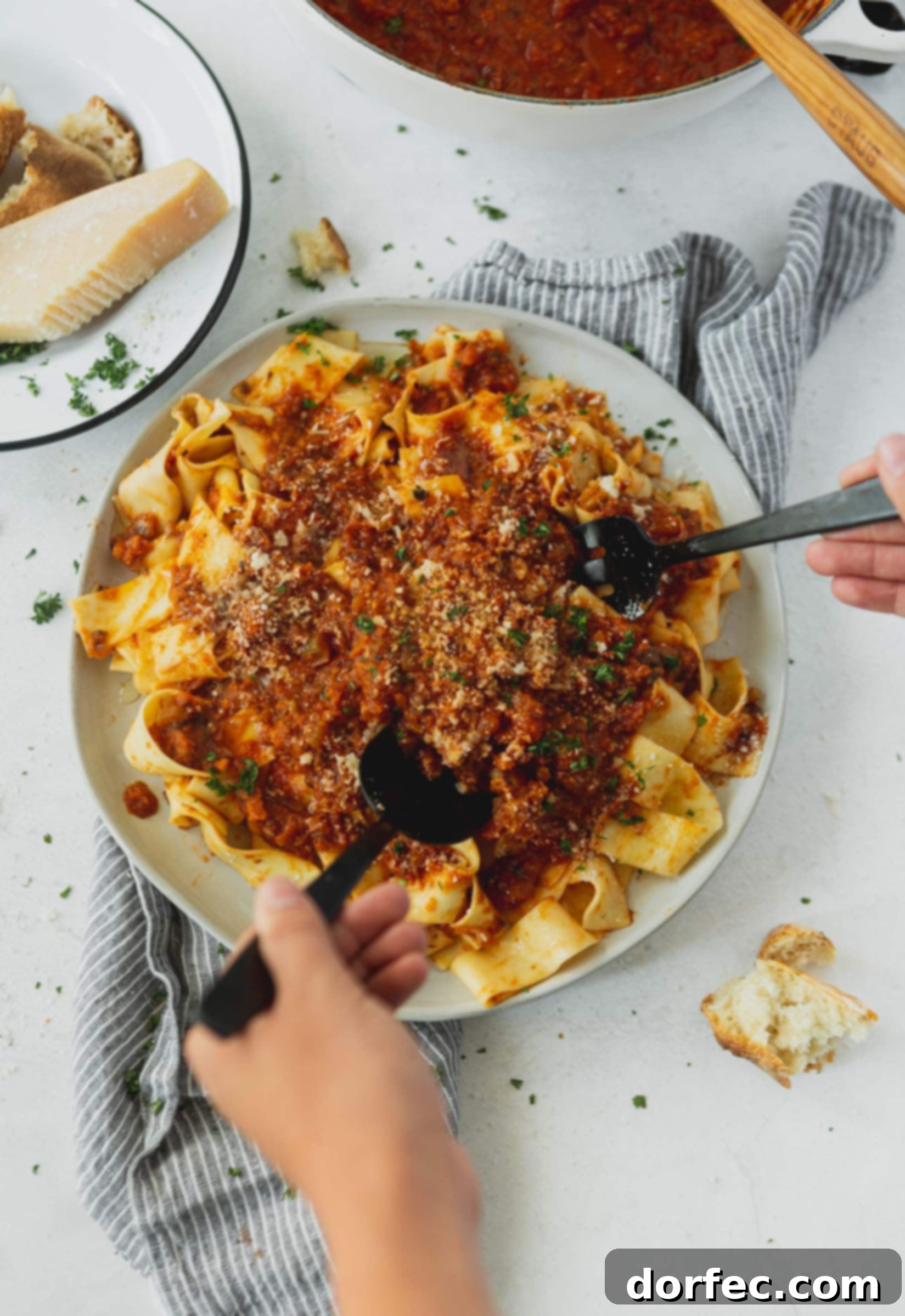 A dinner plate piled with pasta that has a vegan bolognese sauce on top. 