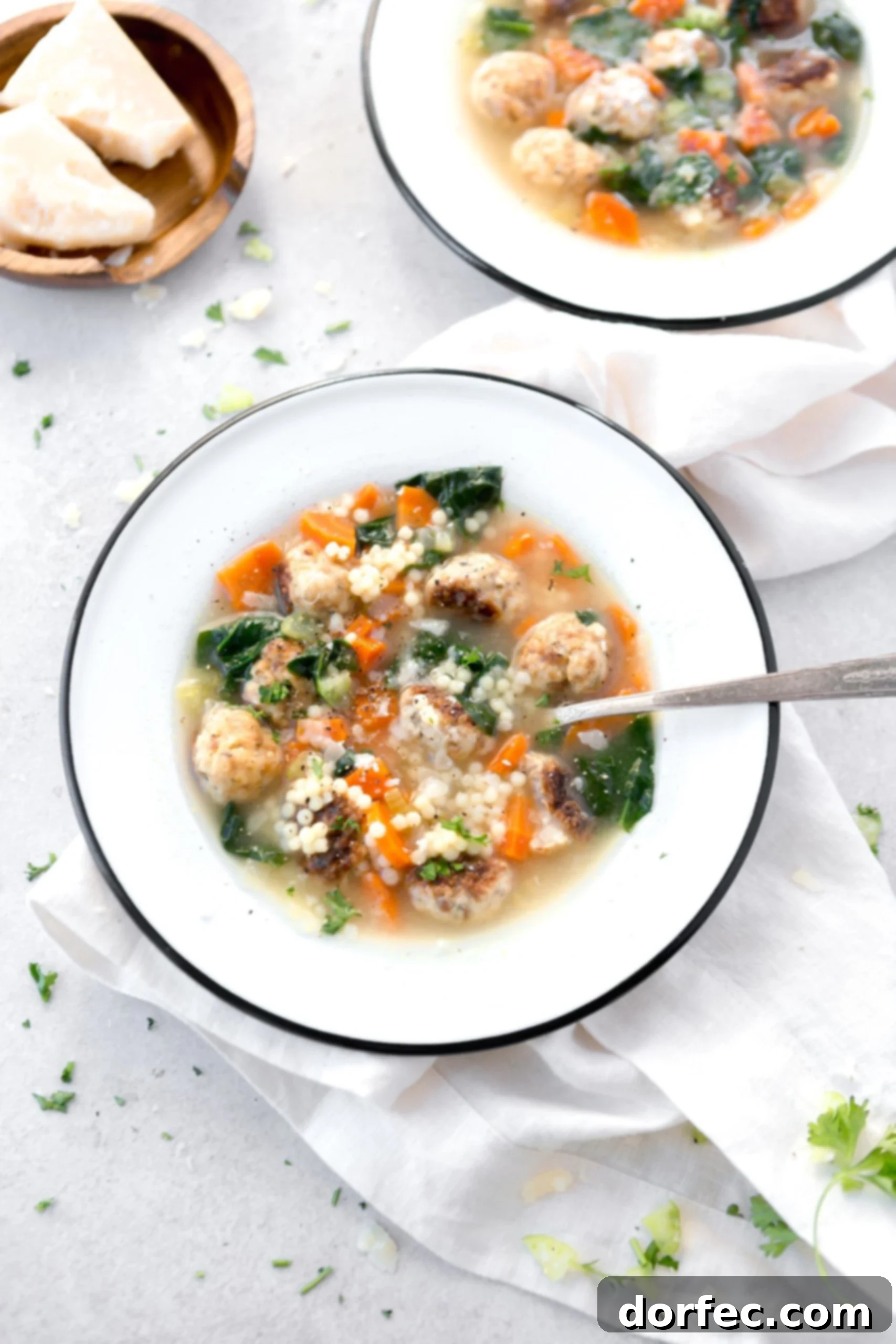 Italian Wedding Soup A bowl of Italian Wedding soup with a spoon in it. The soup is packed with colorful vegetables and meatballs. The bright green spinach brightens up the soup.