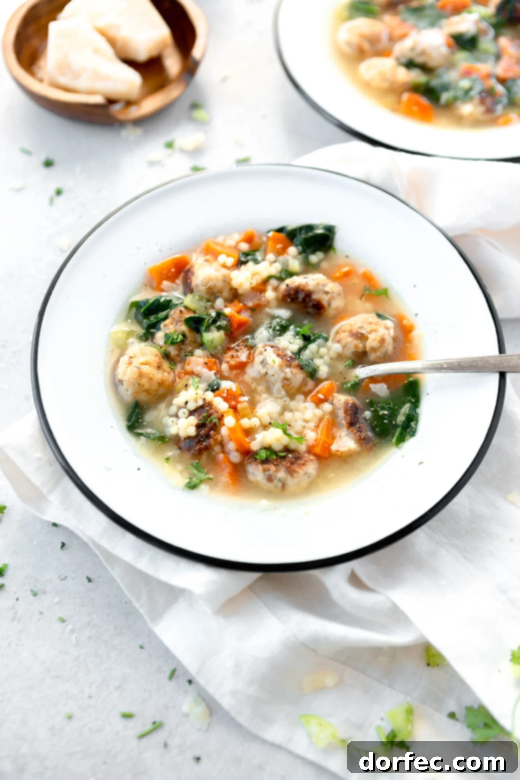 Italian Wedding Soup A bowl of Italian Wedding soup with a spoon in it. The soup is packed with meatballs and carrots and spinach.