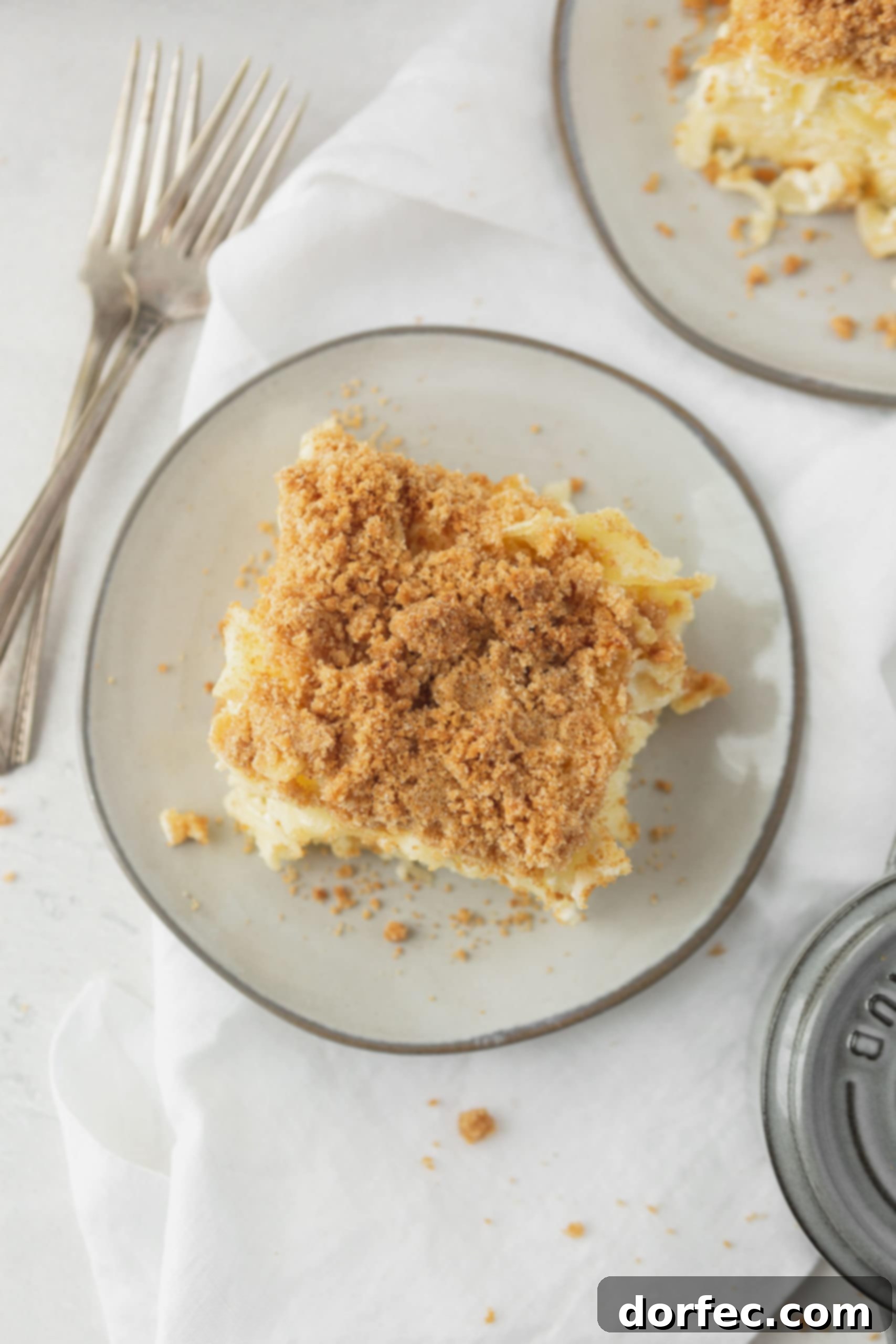 Sweet Noodle Kugel as a Main Dish A perfectly portioned serving of Jewish Kugel on a white plate, ready to be enjoyed. A silver fork rests next to the plate, inviting a taste of the sweet, creamy noodle dish with its crunchy topping.