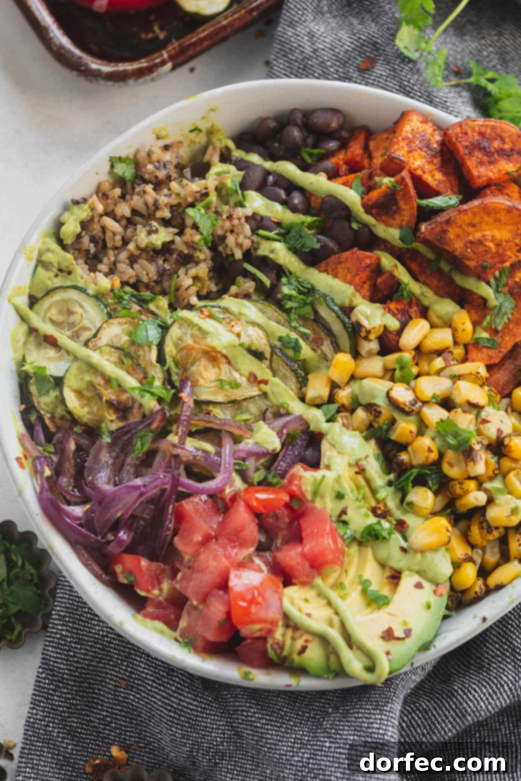 Hearty and Flavorful Plant Powered Burrito Bowls 3 A vegan burrito bowl filled with brown rice, quinoa, roasted corn, tomatoes, black beans, red onions, zucchini and sweet potatoes.