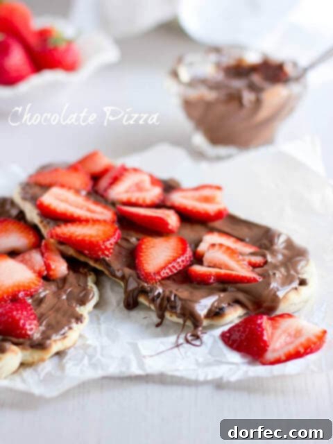 A chocolate pizza topped with Nutella and fresh strawberries, a unique and delicious dessert.