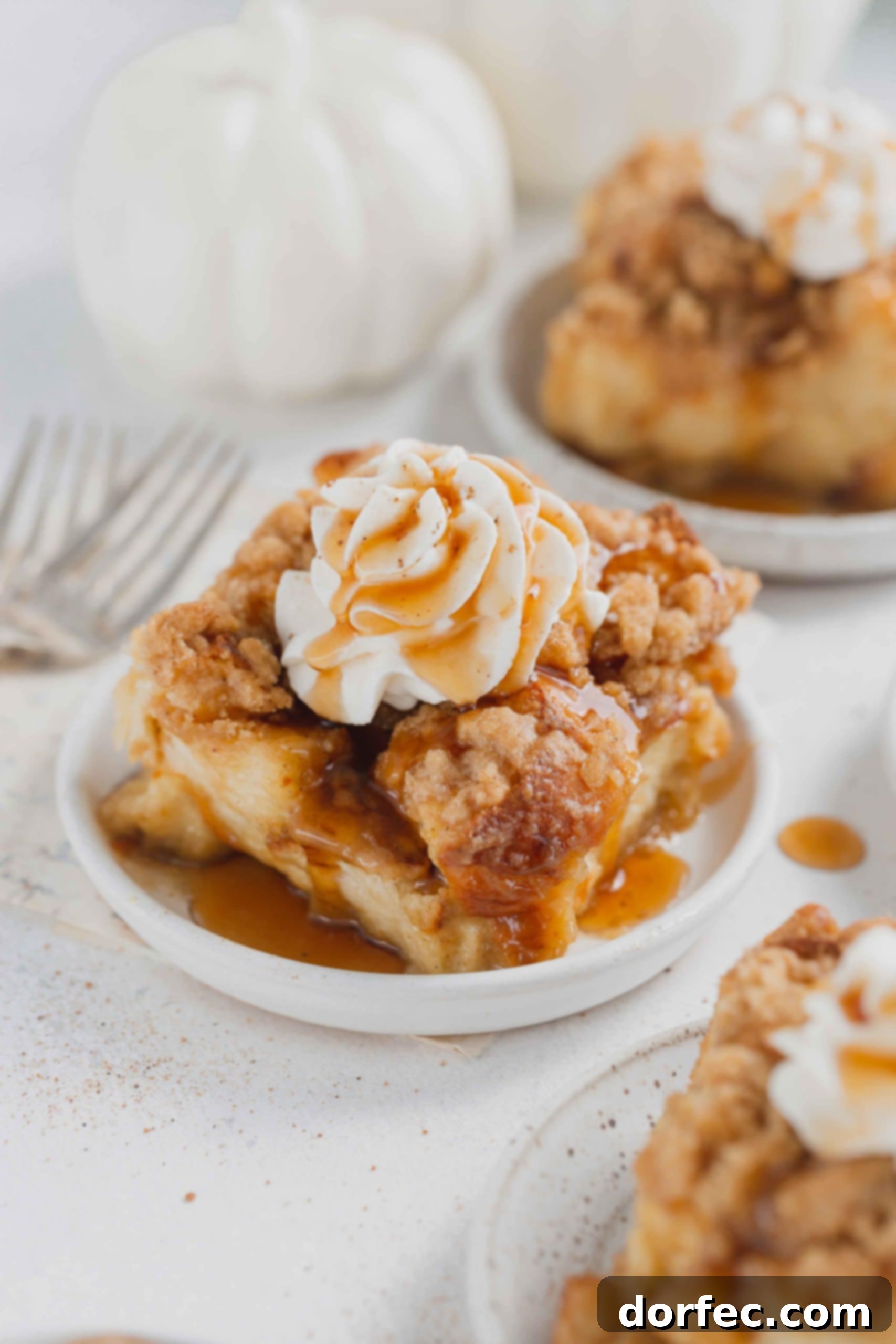 Eggnog french toast casserole on a serving plate. The french toast is topped with whipped cream and a little syrup.