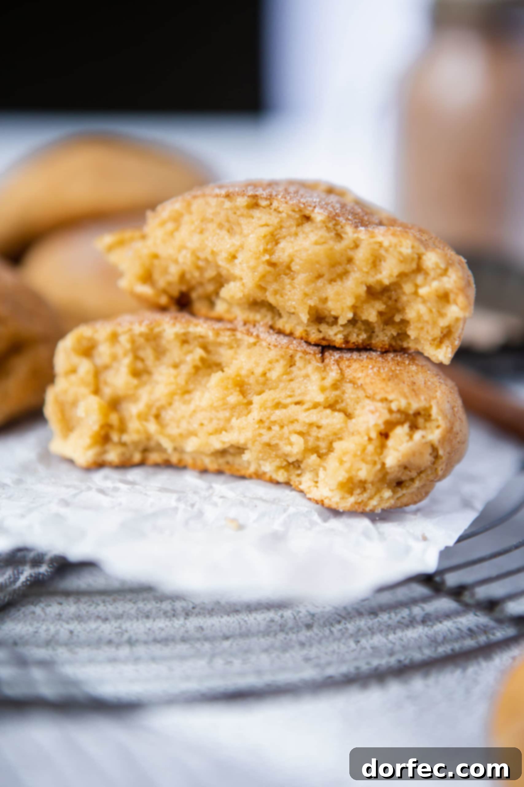 Thick Snickerdoodle Cookies A baked snickerdoodle that is broken in half and the halves are stacked on top of each other.