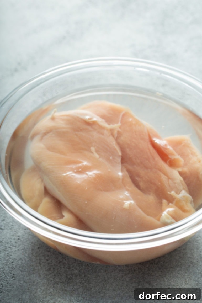 Authentic Southern Crispy Fried Chicken 8 Uncooked chicken breasts in a bowl of salt water.