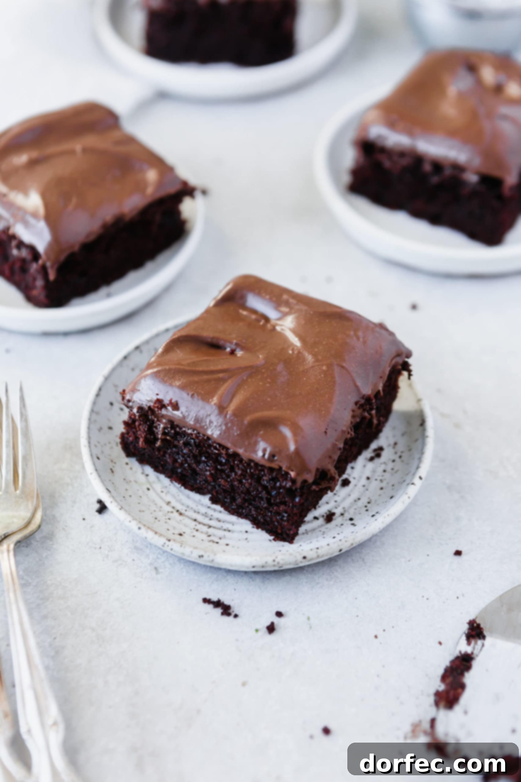 Chocolate Mayonnaise Cake Three elegant white dessert plates, each showcasing a generous serving of chocolate mayonnaise cake generously frosted with chocolate cream cheese frosting.