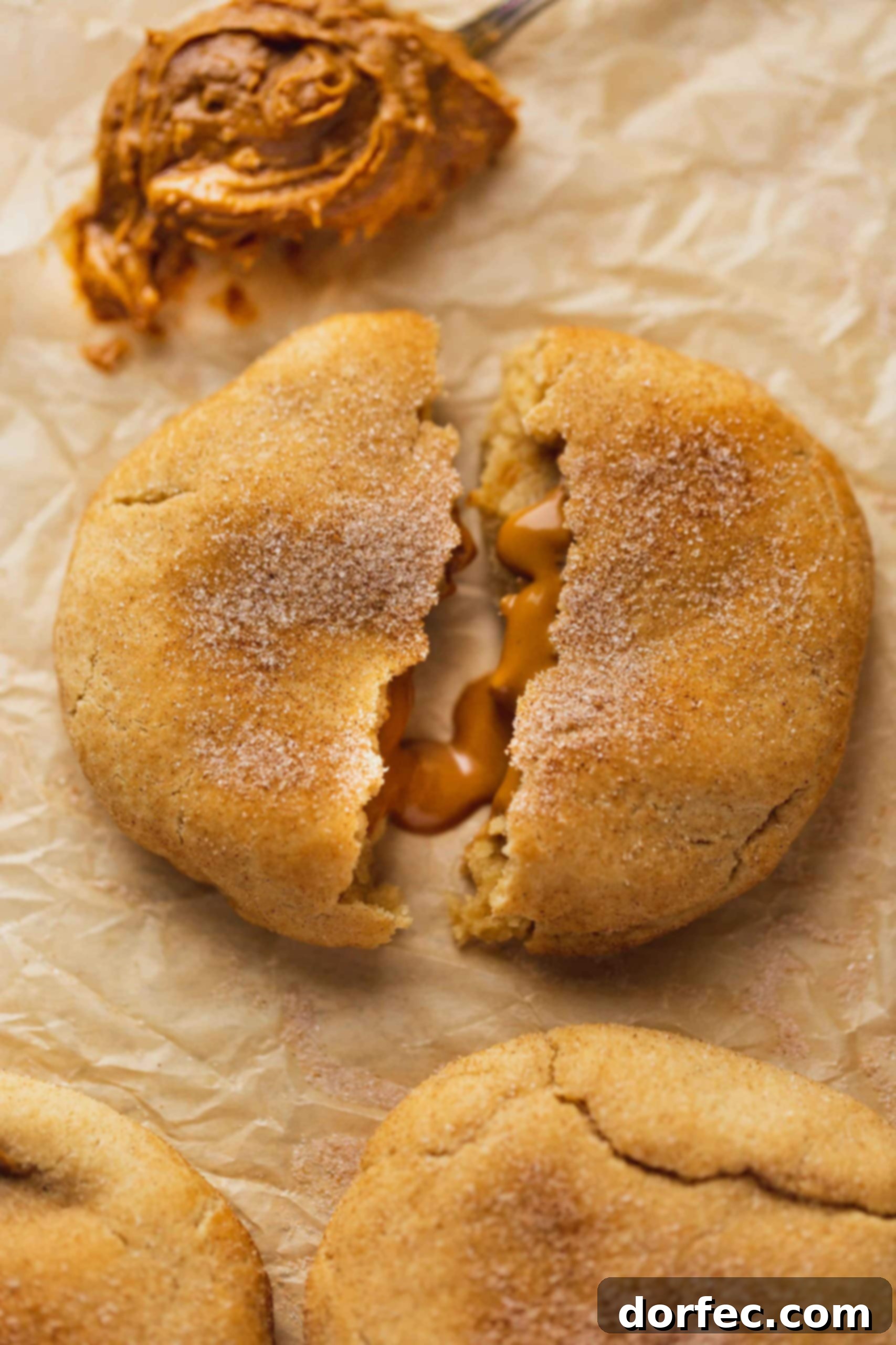 A biscoff stuffed snickerdoodle that is broken in half showing the biscoff oozing our from inside.