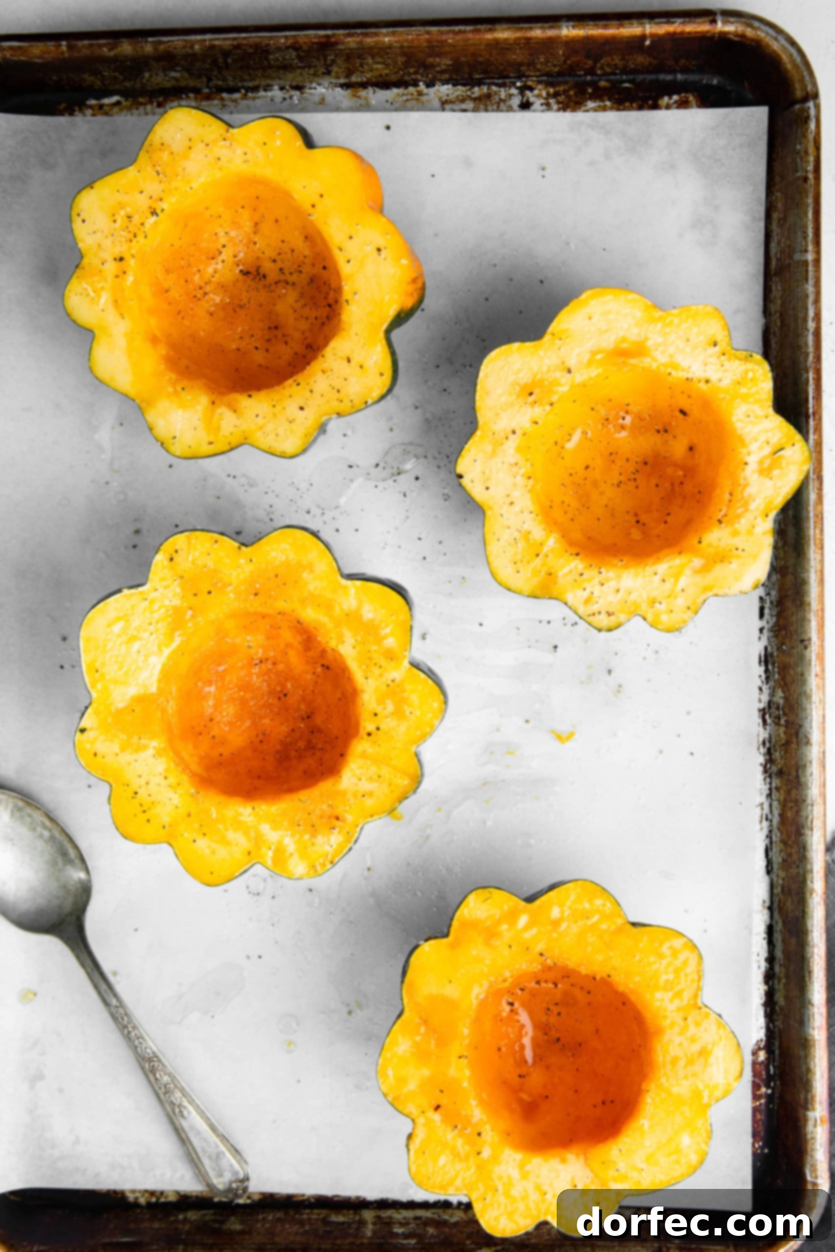 Leftover Thanksgiving Turkey and Stuffing Acorn Squash a photo of four halves of acorn squash brushed with oil and sprinkled with salt and pepper sitting case up on a cookie sheet lined with parchment paper.