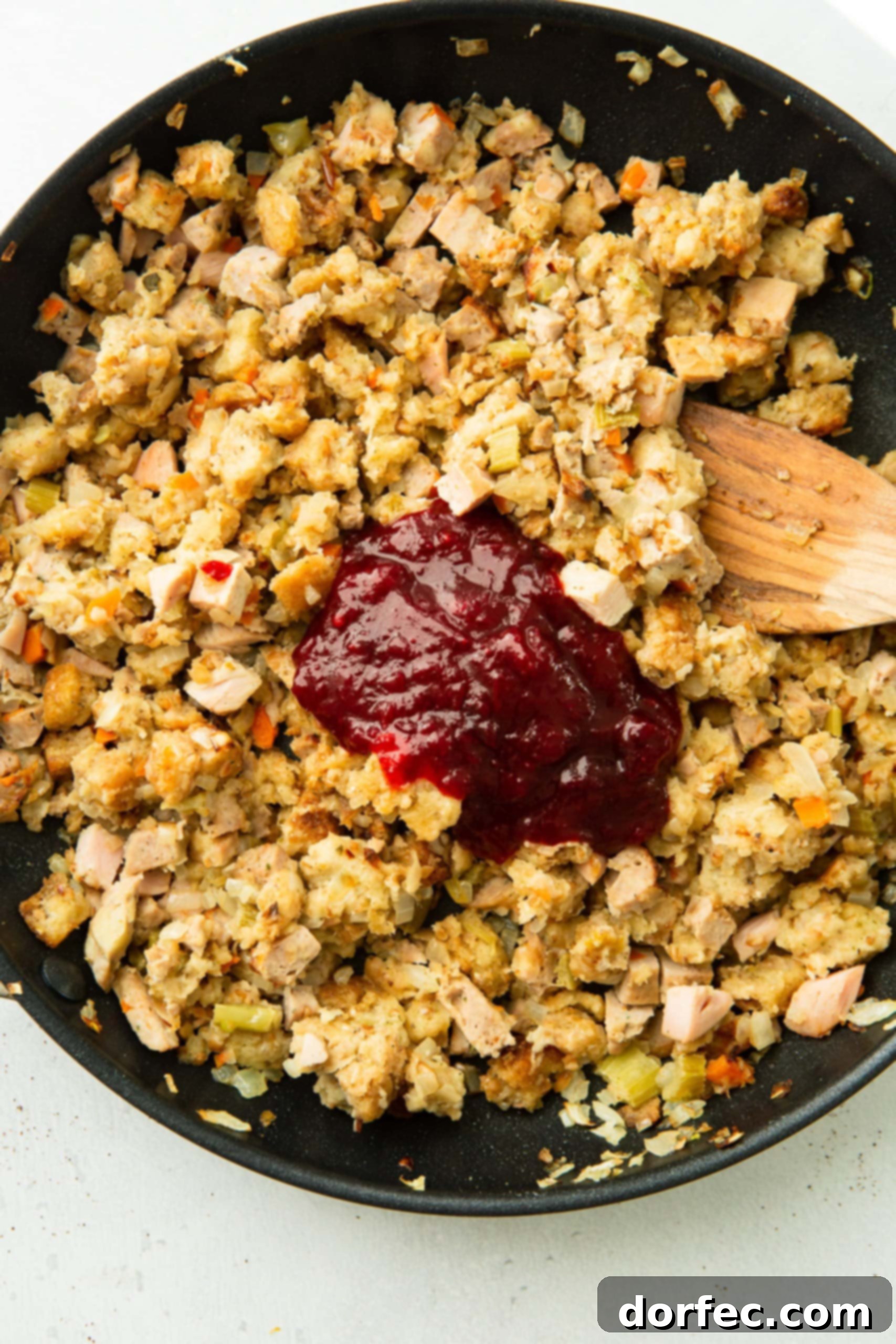 Leftover Thanksgiving Turkey and Stuffing Acorn Squash a photo of a skillet filled with turkey, stuffing and a dollop of cranberry sauce on top.