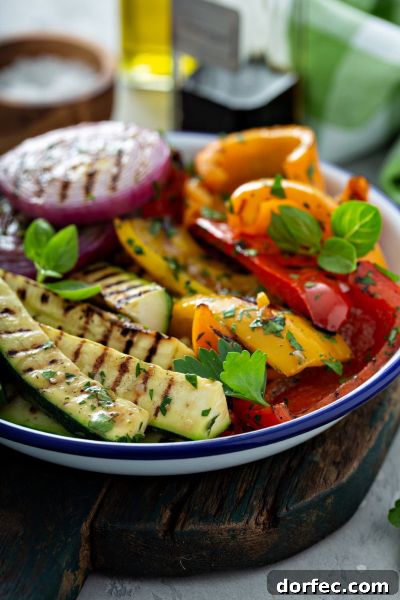 A serving dish of grilled zucchini, red and yellow bell peppers, and red onions. There are golden grill marks on the vegetables and parsley leaves sprinkled on top.