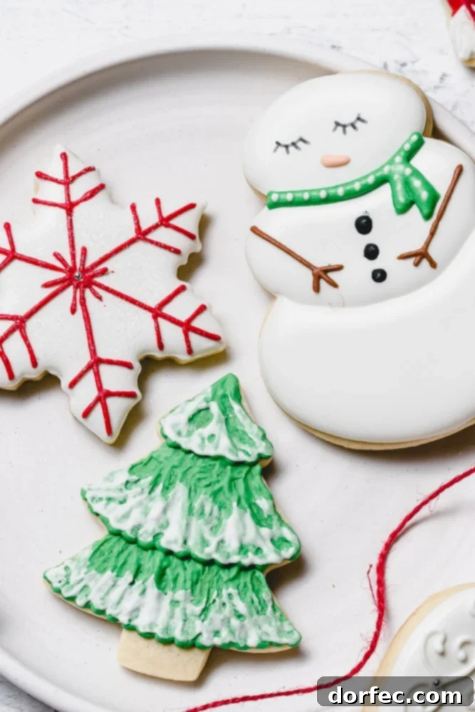 Festive Glaze for Holiday Cookies 2 Decorated Christmas sugar cookies featuring a jolly snowman with a green scarf, a festive green Christmas tree adorned with white snow accents, and an elegant white star with delicate red designs.