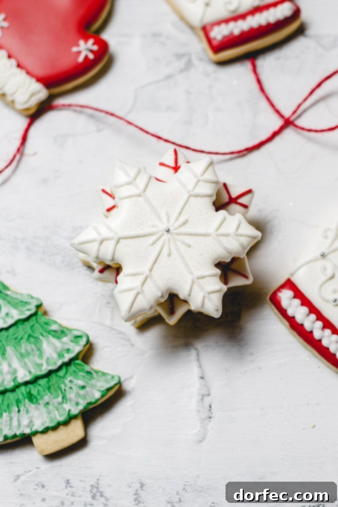 Festive Glaze for Holiday Cookies 6 A festive close-up of Christmas sugar cookies, showcasing a crisp white snowflake with delicate white accents and a vibrant green Christmas tree topped with snowy white details.