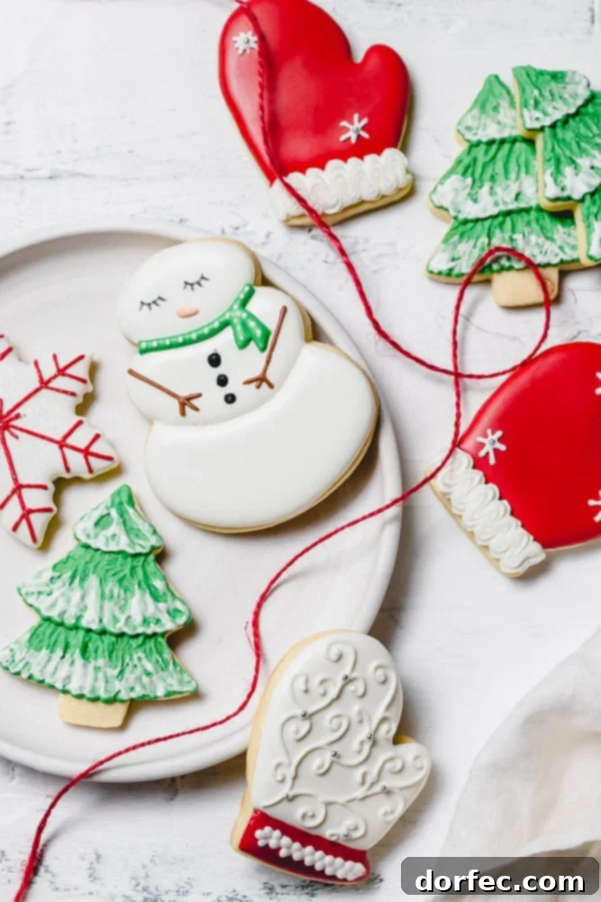 Festive Glaze for Holiday Cookies 7 An array of festive Christmas sugar cookies elegantly decorated with royal icing. Designs include a charming snowman with a green scarf, a cozy red mitten, a delicate snowflake with red accents, and a vibrant green Christmas tree adorned with white snow.