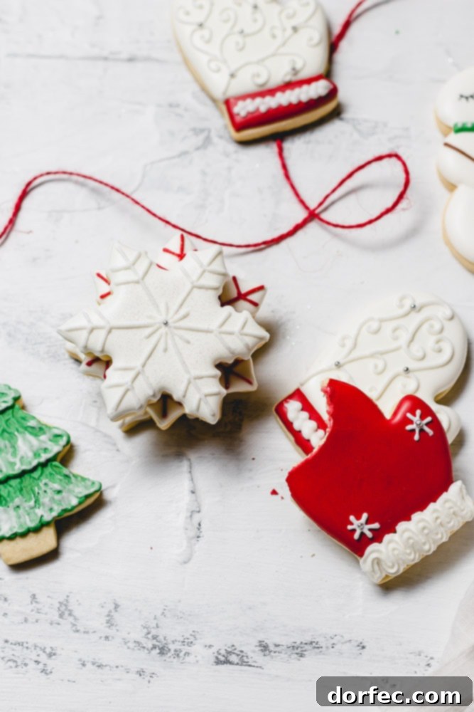 Festive Glaze for Holiday Cookies 8 A festive assortment of Christmas sugar cookies adorned with royal icing. The collection features pristine white snowflakes, vibrant red mittens, classic white mittens with red trim, and a cheerful green Christmas tree dusted with white snow.