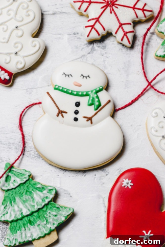 Festive Glaze for Holiday Cookies 9 A festive collection of Christmas sugar cookies adorned with delicate royal icing. The plate features a charming snowman with a green scarf, a vibrant green Christmas tree dusted with white snow, a cozy red mitten, and a classic white mitten.