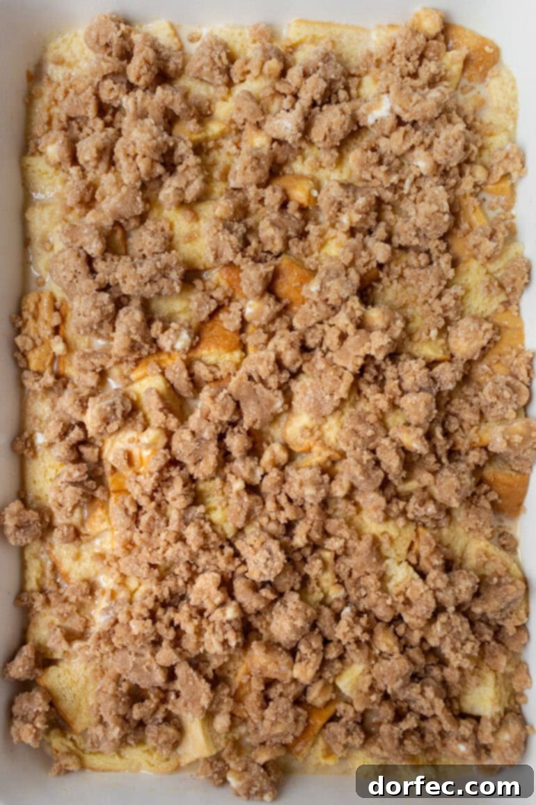 Overnight French Toast Bake 8 An unbaked French toast casserole, with the bread thoroughly soaked in custard and ready to be topped with streusel before baking.