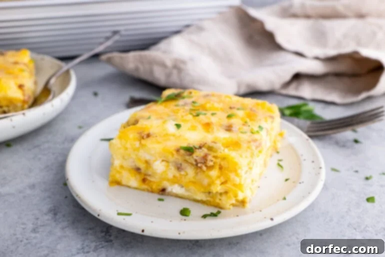 A photo of a piece of cheesy sausage breakfast souffle sitting on a small plate, showcasing its golden-brown crust and fluffy interior.