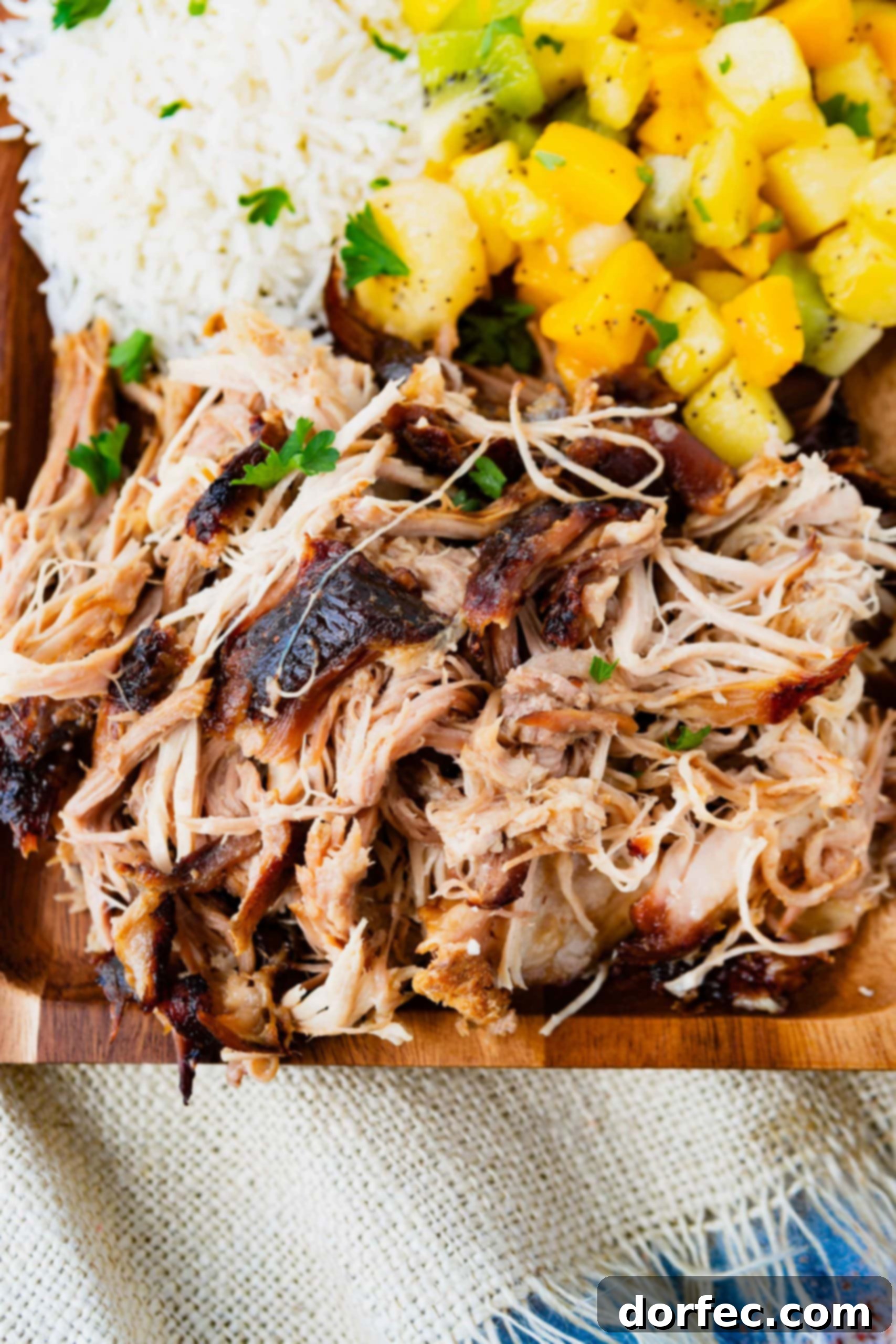 A photo of tender, juicy kalua pulled pork on a wooden serving platter.