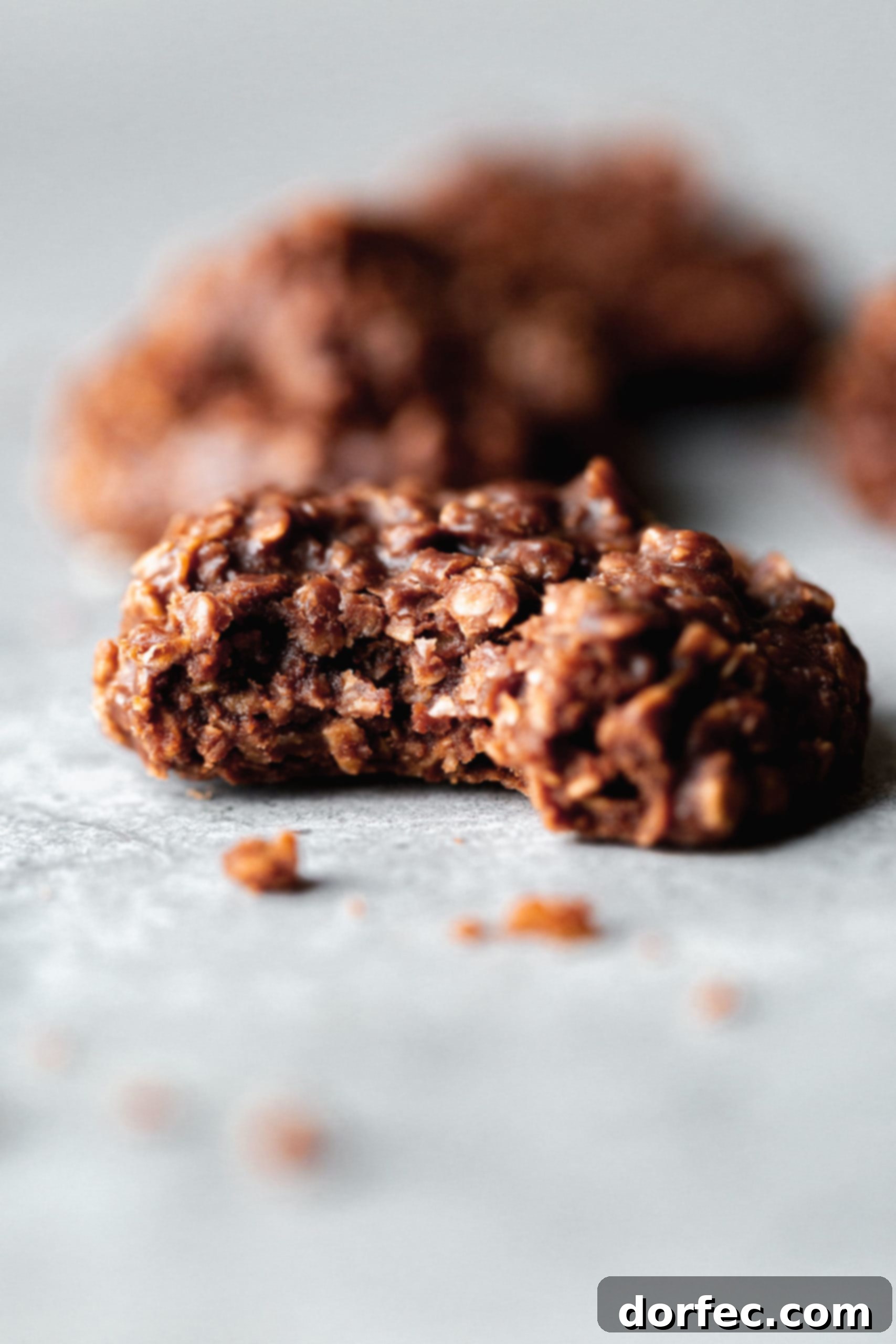 A single chocolate no-bake cookie with a bite taken out, revealing its oatmeal and chocolate texture.