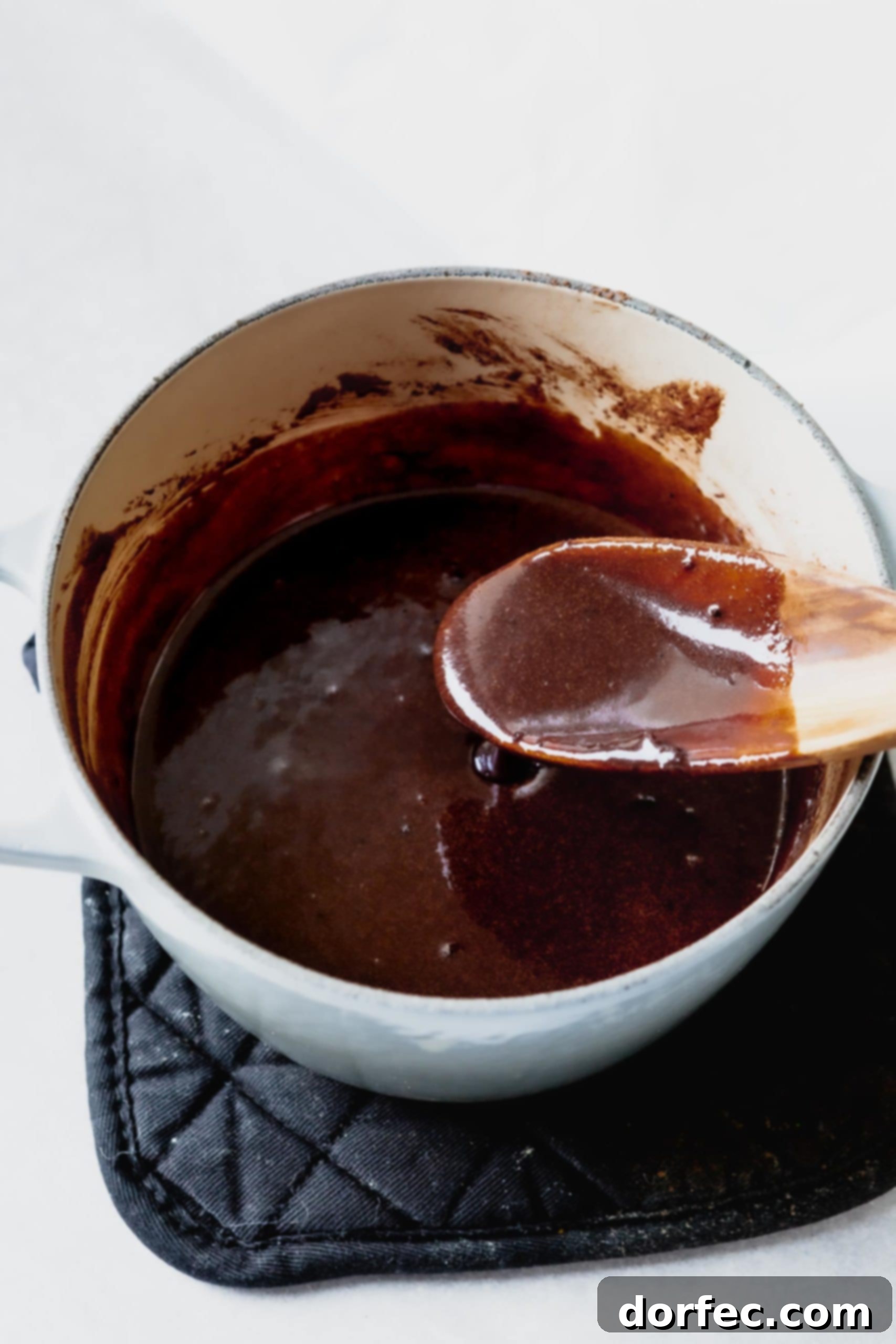 A saucepan filled with a melted, glossy chocolate mixture of milk, sugar, butter, and cocoa, ready for the next steps.