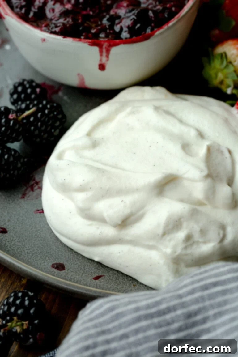 A generous pile of perfectly whipped vanilla bean whipped cream, glistening and creamy, ready to be served alongside fresh, vibrant berries.