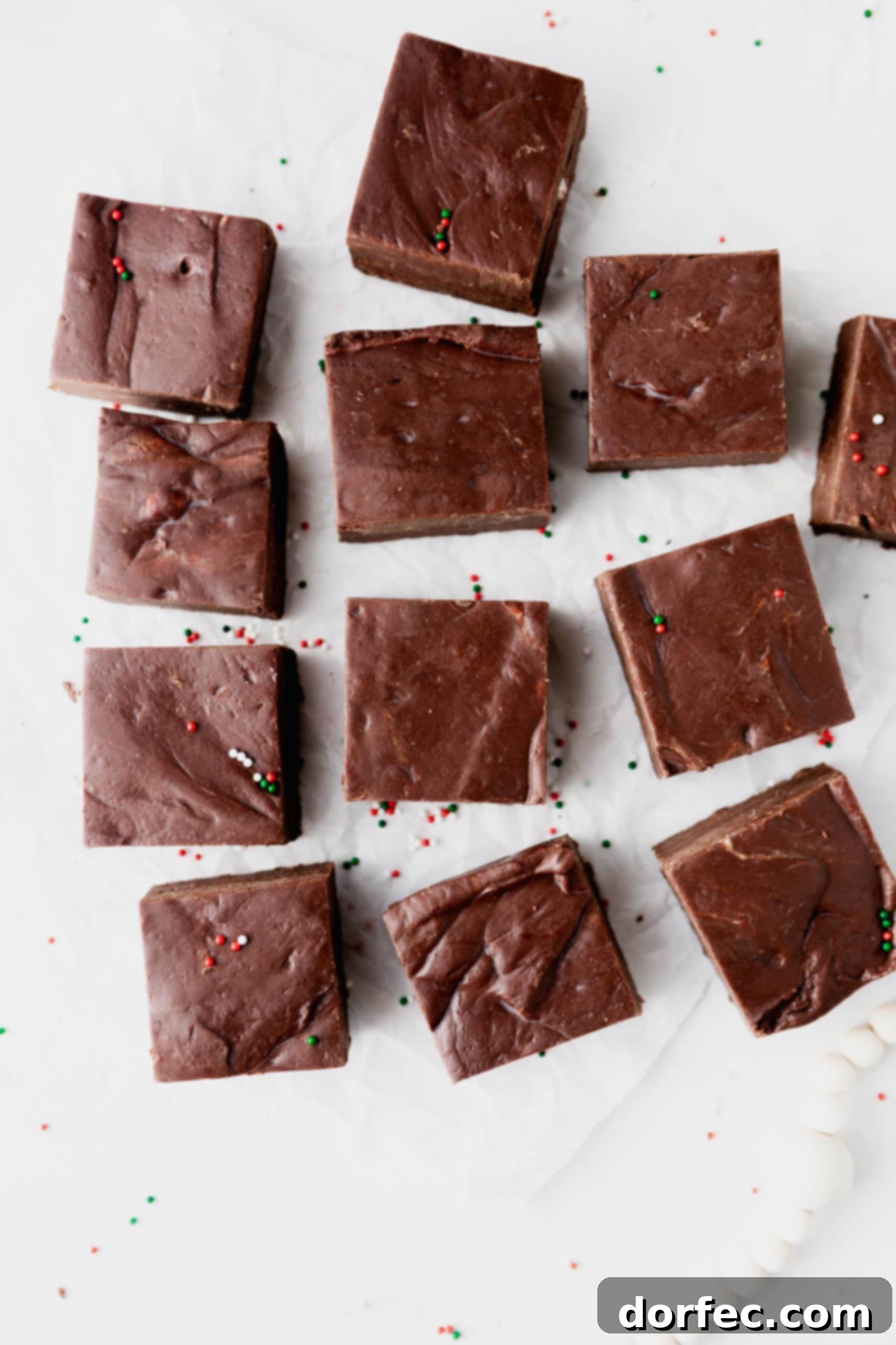 12 perfectly square pieces of chocolate fudge neatly arranged on a piece of parchment paper, highlighting their uniform size and appealing texture.