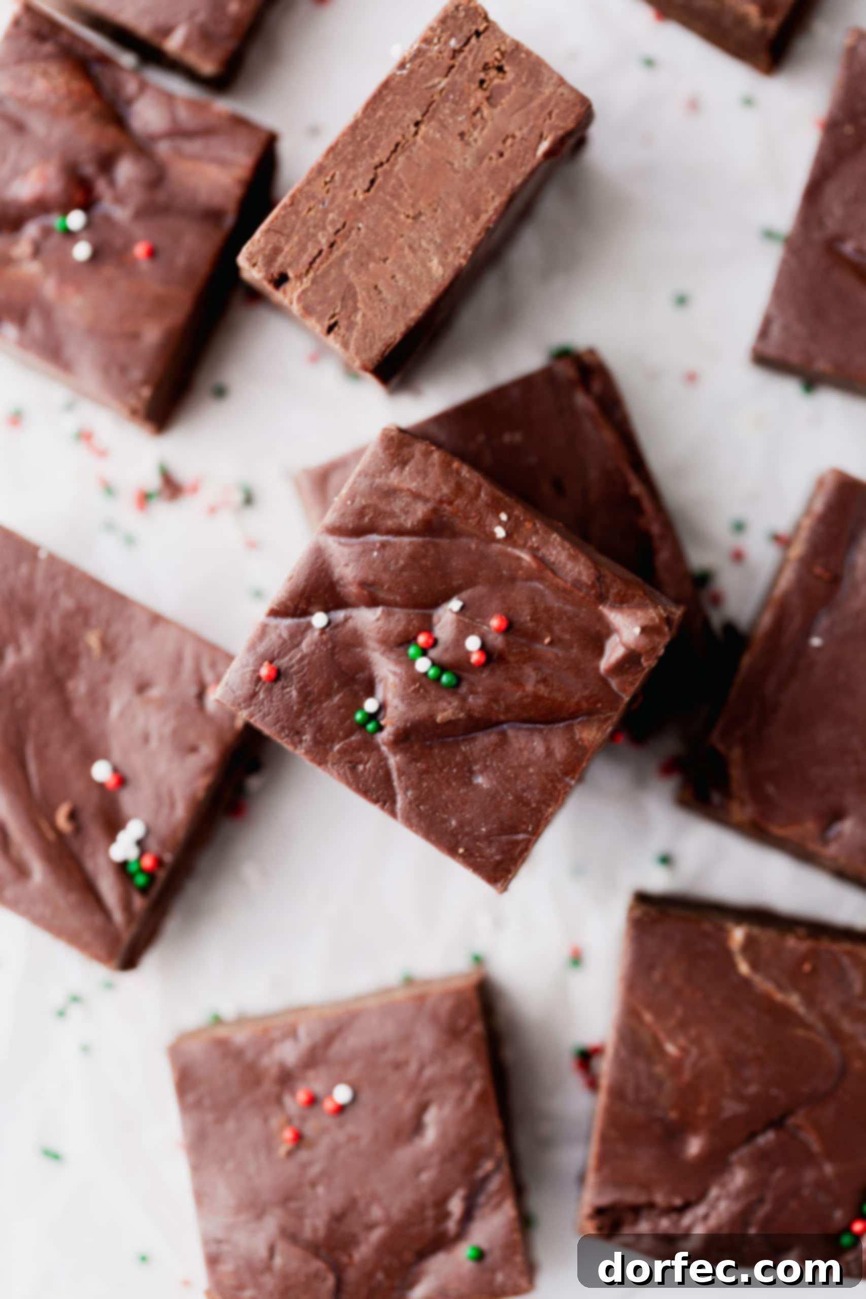 A charming plate showcasing homemade chocolate fudge, neatly cut into squares and adorned with festive red and green sprinkles, perfect for holiday gatherings.