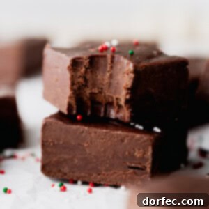 A vibrant close-up of a plate of homemade fudge, cut into neat squares and garnished with red and green sprinkles, emphasizing its appealing texture and festive presentation.