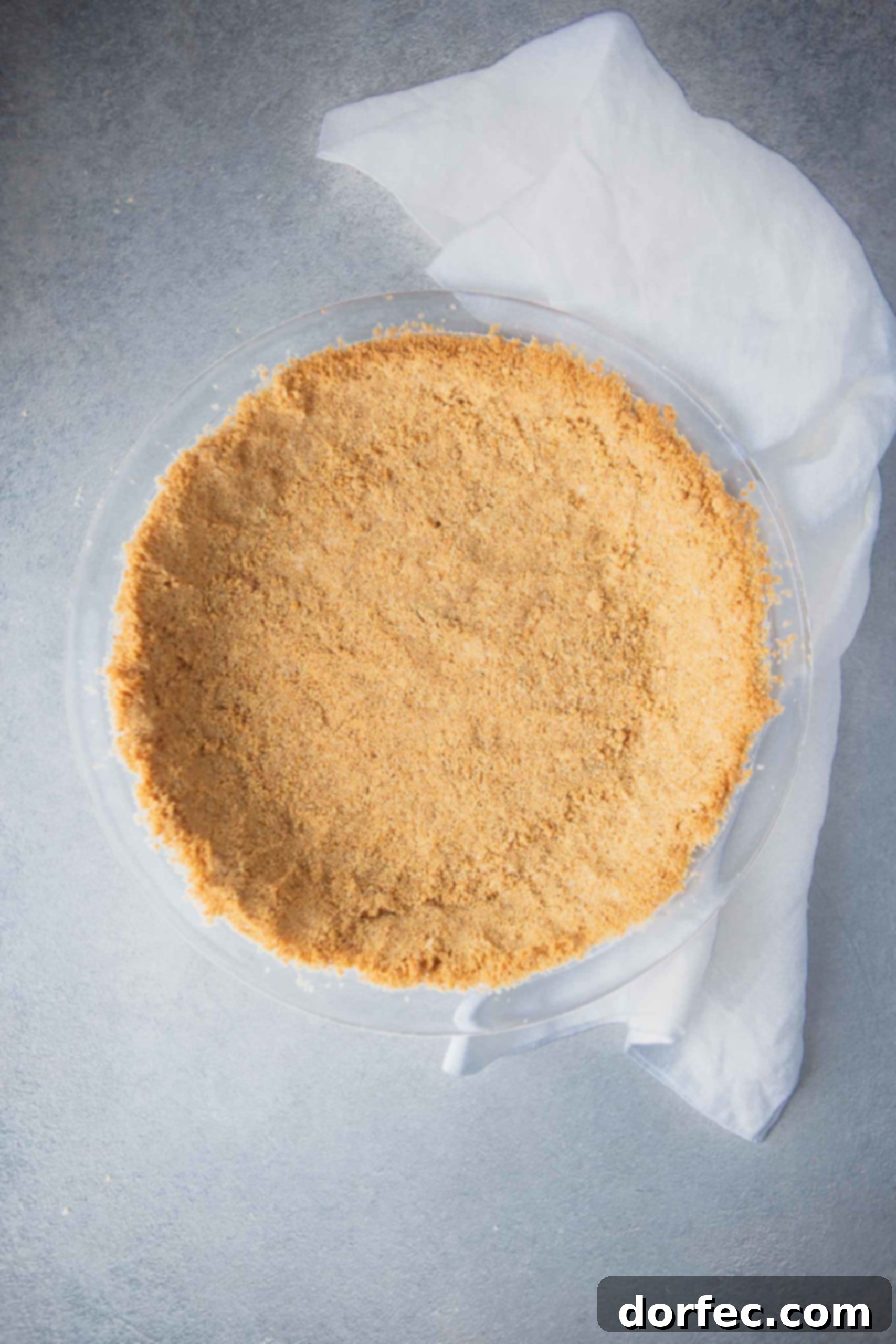 Graham Cracker Crust A perfectly pressed homemade graham cracker crust in a silver pie dish, ready for baking or a no-bake filling.