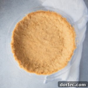 A prepared graham cracker crust for a recipe, showing the golden-brown base set in a pie dish.
